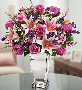 Pink roses and lilies arranged in a clear glass vase