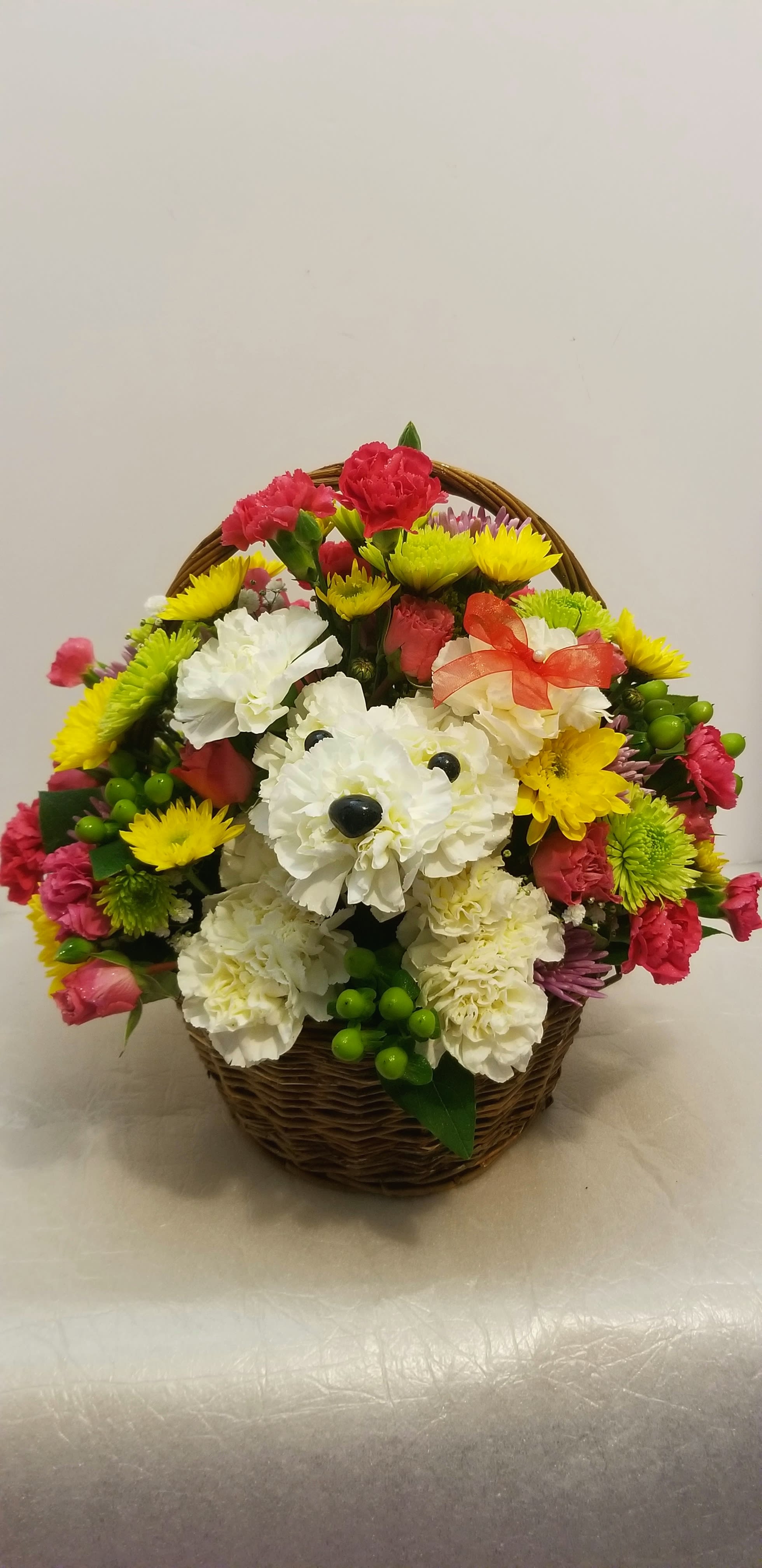 Basket arrangement with white and pink carnations and yellow daisies