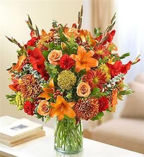 Mixed bouquet of orange, red, and peach flowers in a glass vase