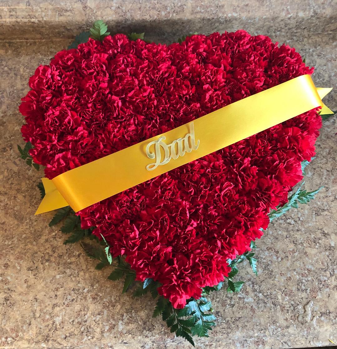 Heart-shaped red carnation arrangement with a yellow ribbon reading Dad