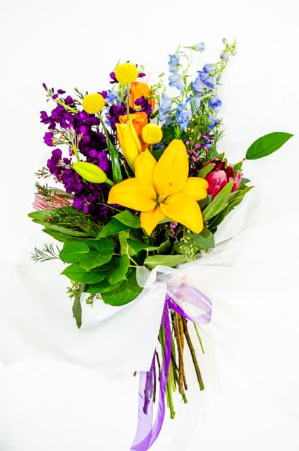 Colorful bouquet with yellow lilies, purple flowers, and blue blooms wrapped in white paper