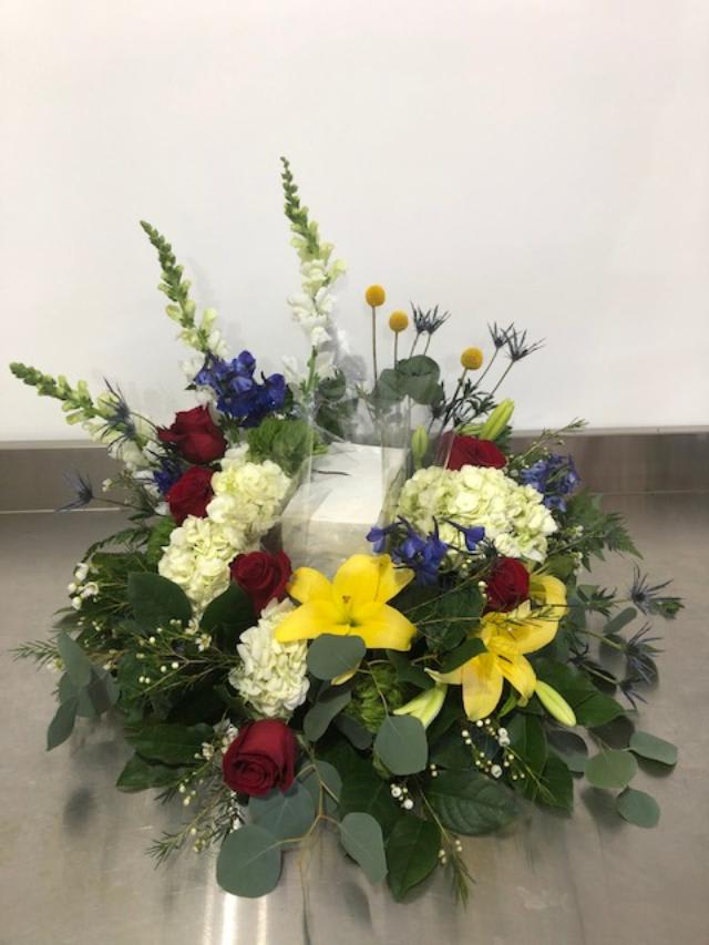Low floral arrangement with red roses, yellow lilies, and white hydrangeas