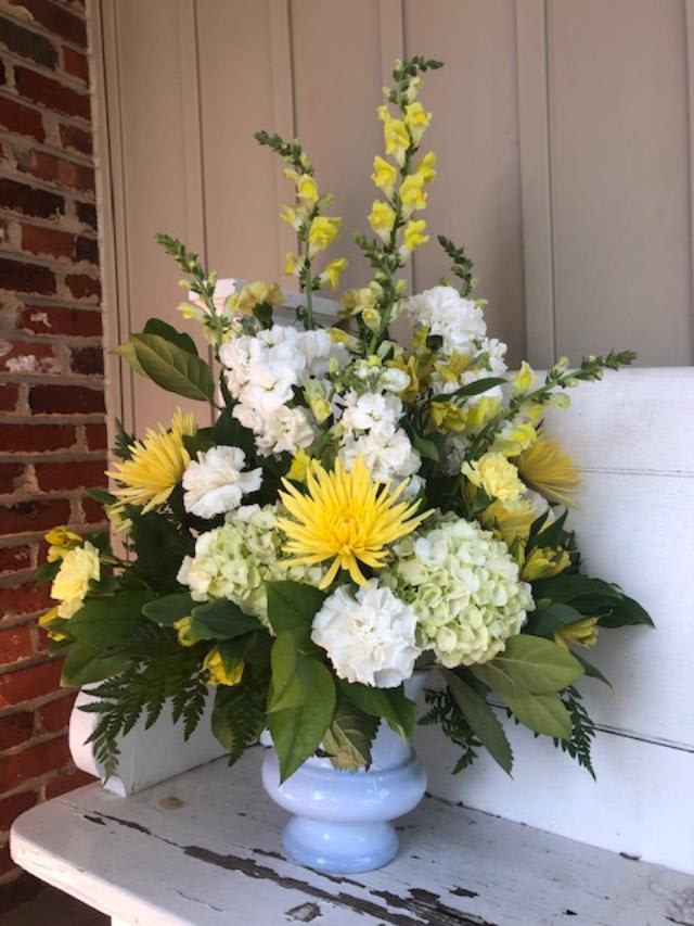 Yellow and white floral arrangement in a light blue vase