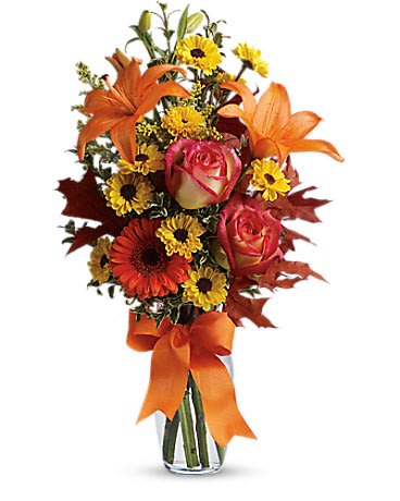 Burst Of Autumn by Teleflora - A burst of beauteous blooms in autumn shades of orange and yellow is mixed with a handful of oak leaves, then delivered in a clear glass vase adorned with a bright satin ribbon. A splendid gift for birthdays or any fall occasion