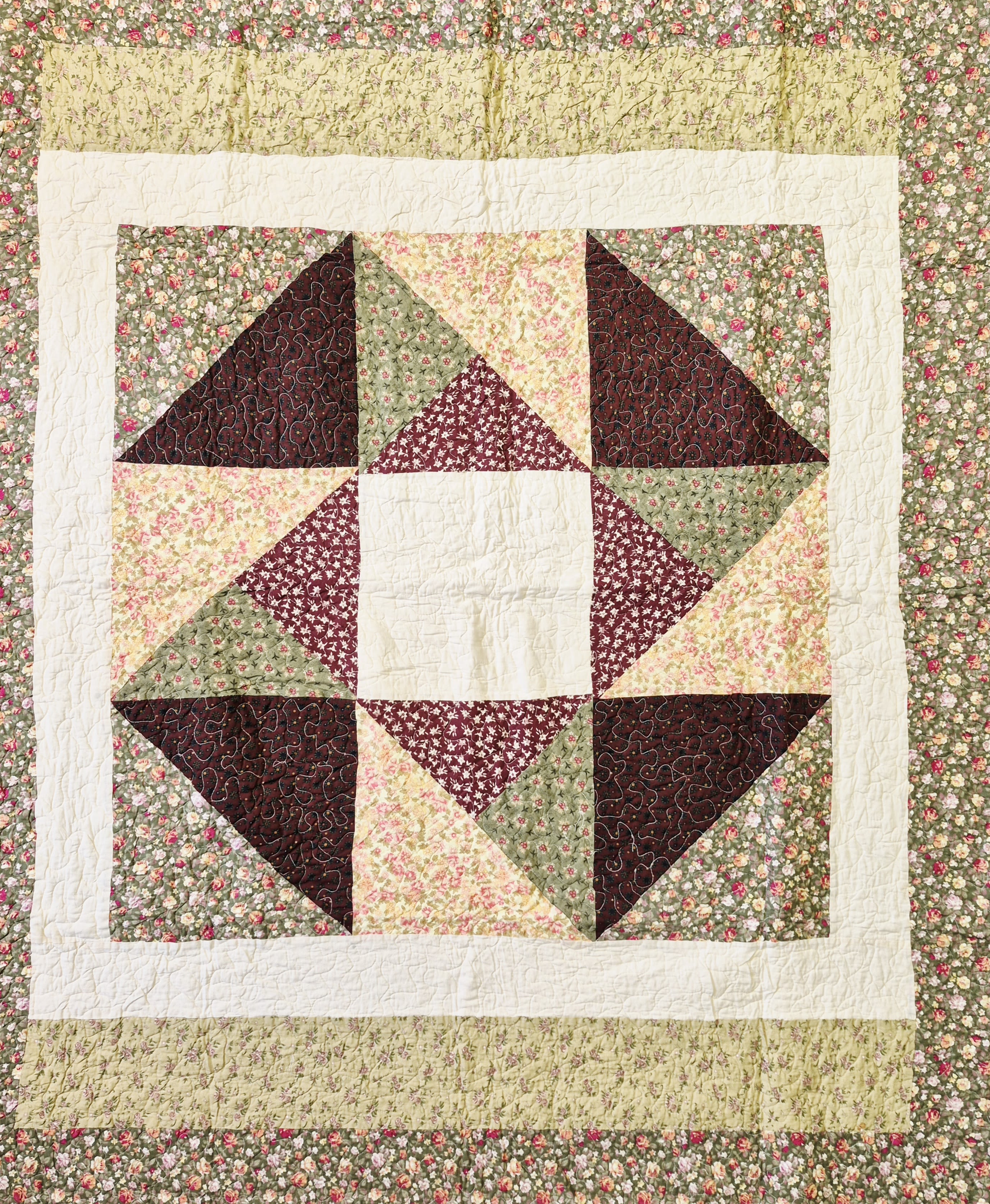 Patchwork quilt with floral prints and a star pattern in burgundy, green, and cream