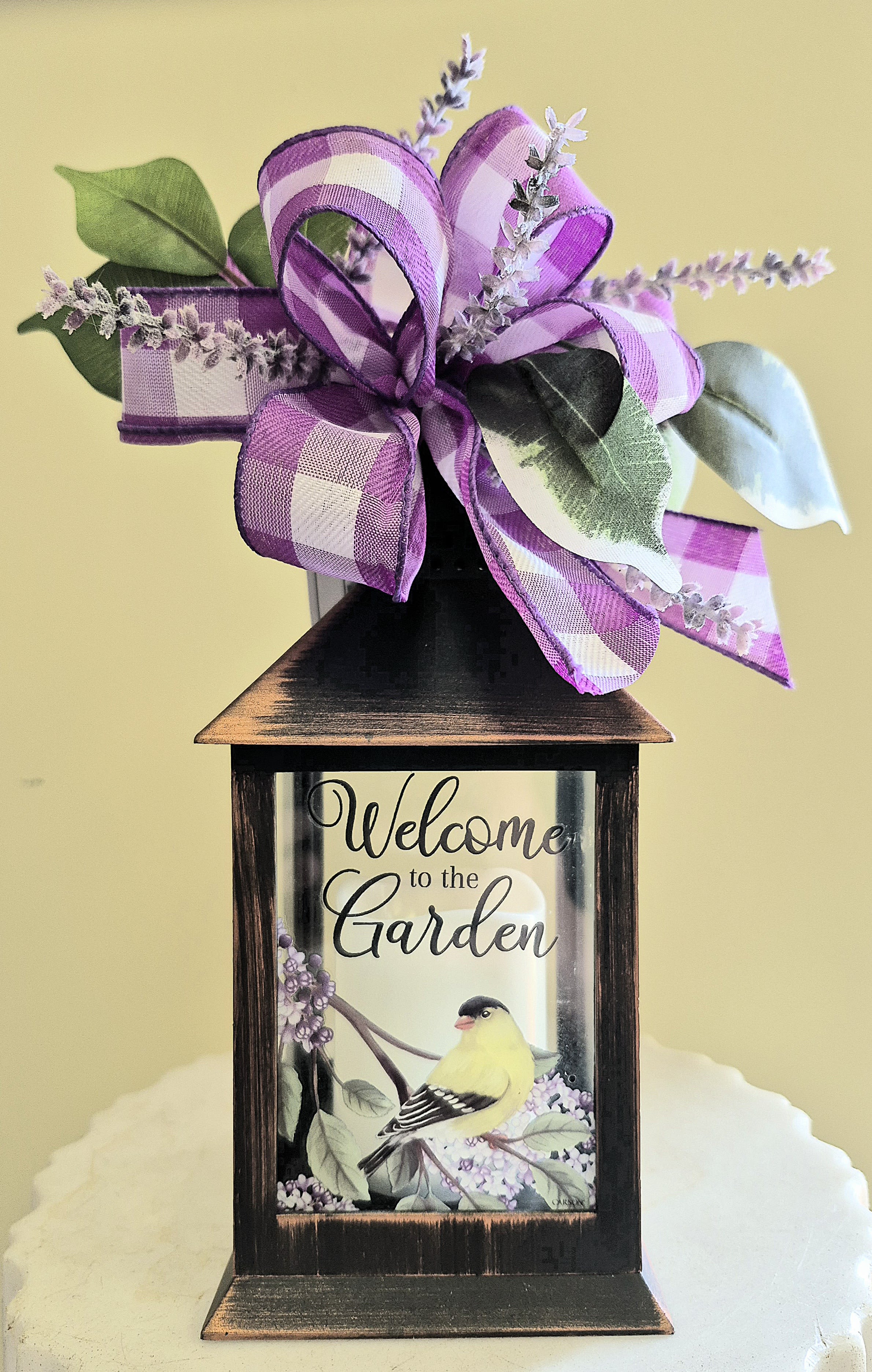 Decorative lantern with a purple ribbon bow and faux greenery