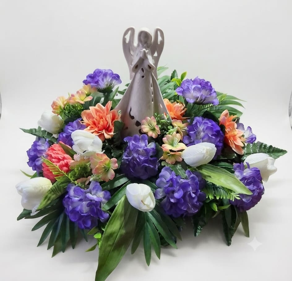 Purple and white floral arrangement with orange accents around a ceramic angel figurine