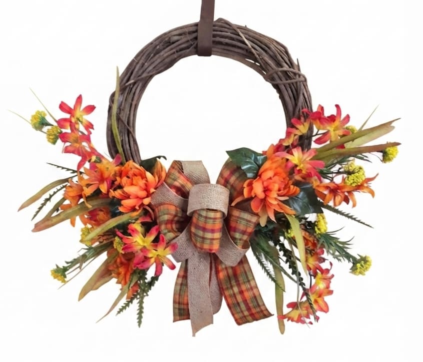 Fall wreath with orange flowers and a plaid bow on a grapevine ring
