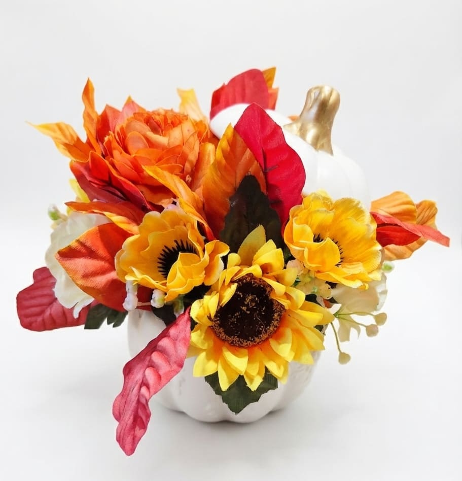 Artificial autumn floral arrangement in a white pumpkin vase