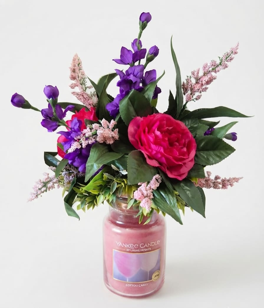 Pink and purple floral arrangement in a glass candle jar