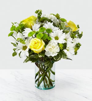 Yellow roses and white daisies in a clear glass vase