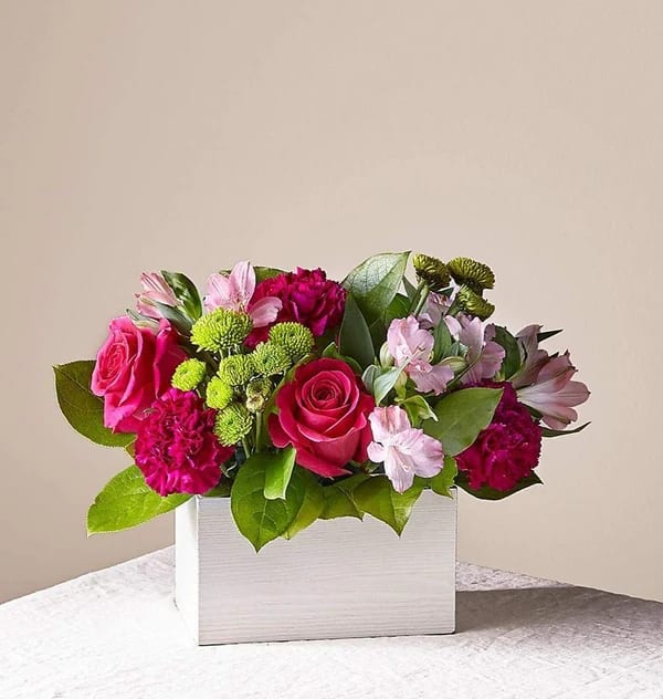 Pink roses and mixed blooms arranged in a white box