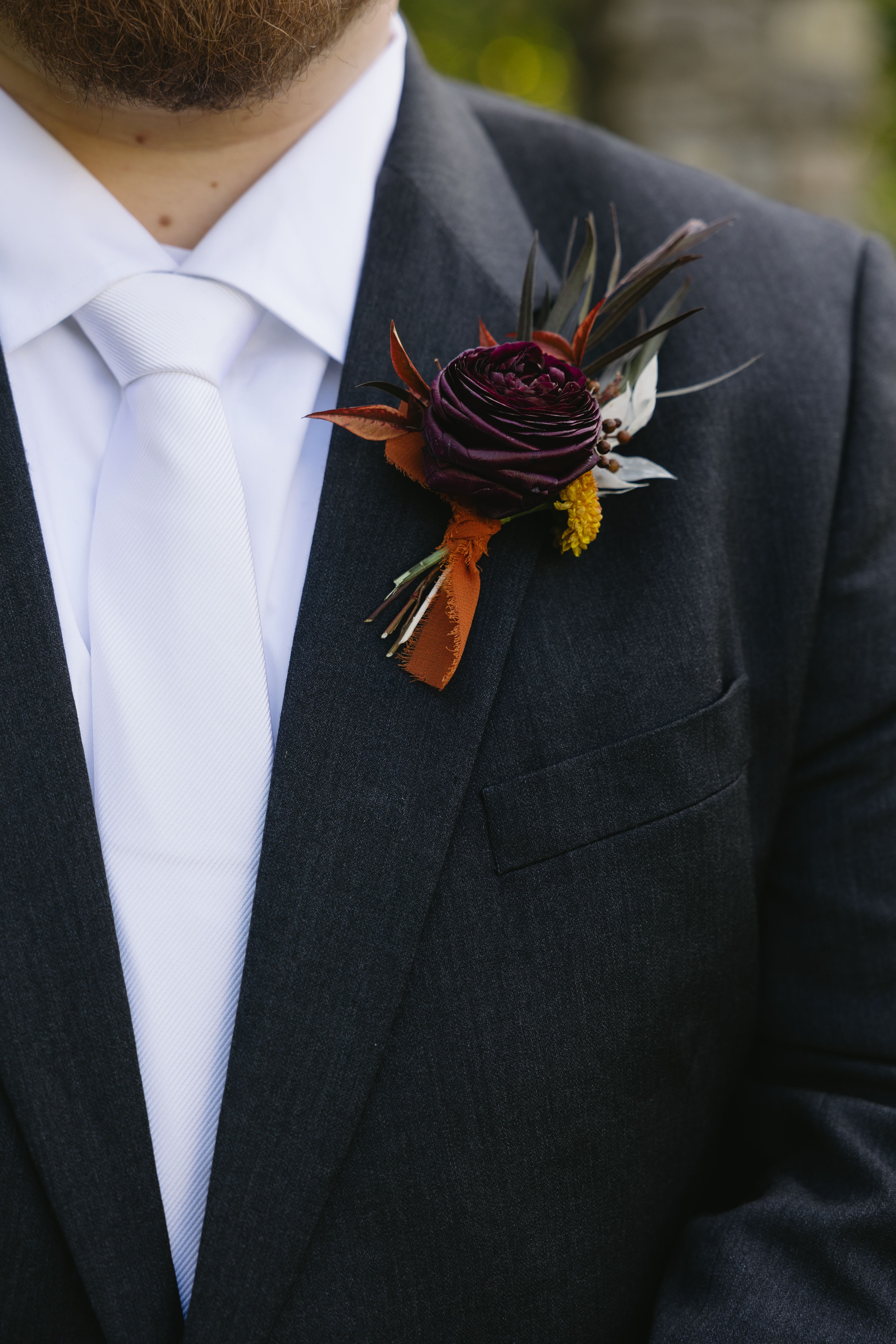Dark floral boutonniere pinned to a black suit jacket