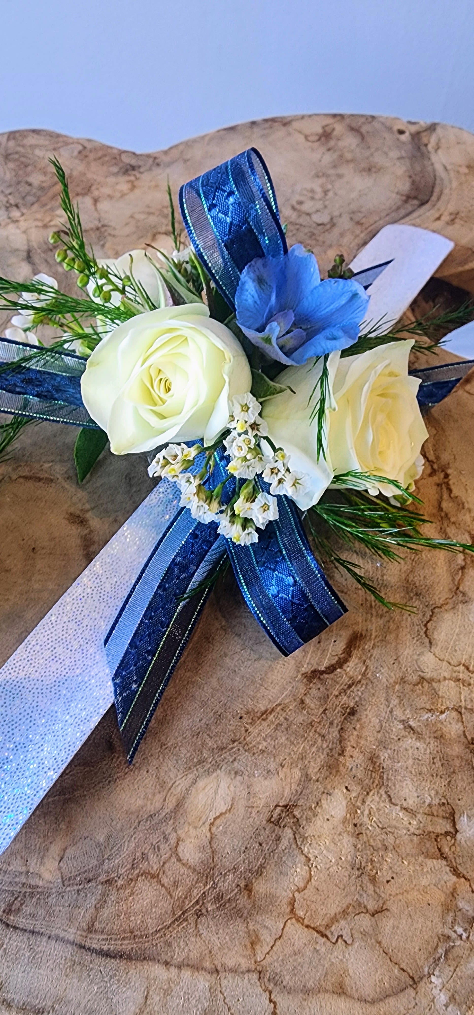 White roses with a blue flower and ribbon accents
