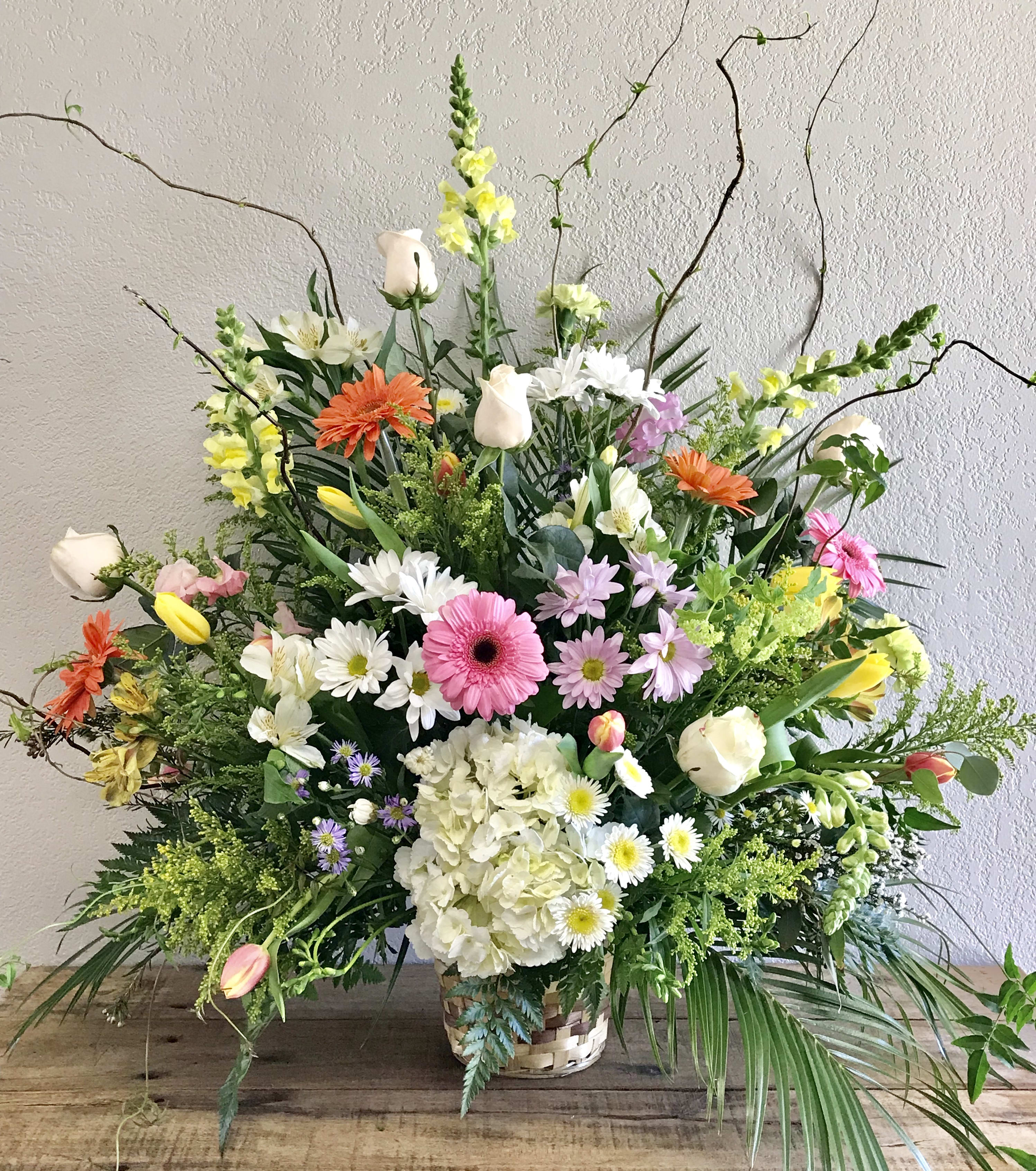 Large mixed flower arrangement in a woven basket with white, pink, and orange blooms