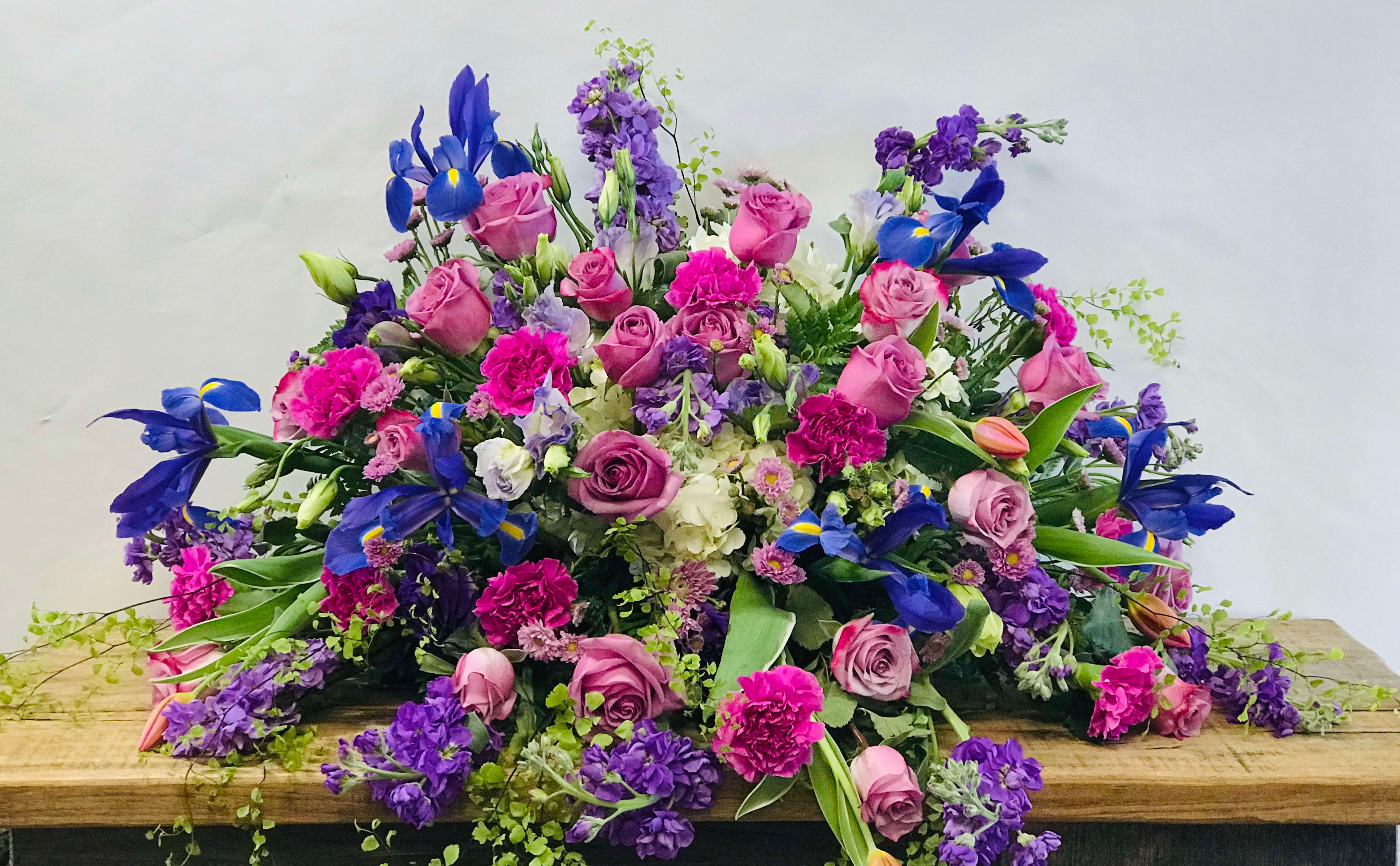 Large mixed bouquet of pink, purple, and blue flowers on a wooden surface