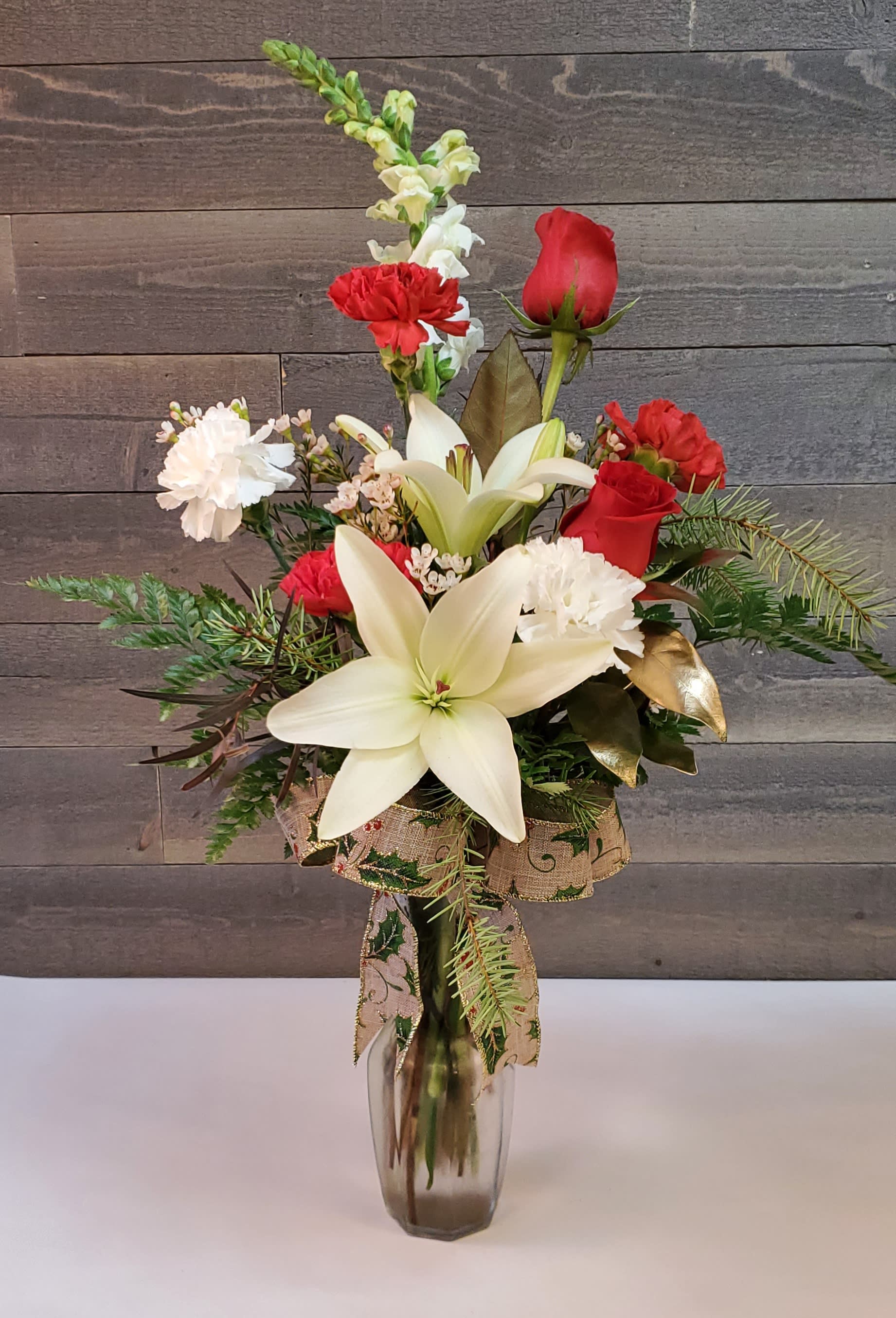 Red roses and white lilies in a glass vase with carnations