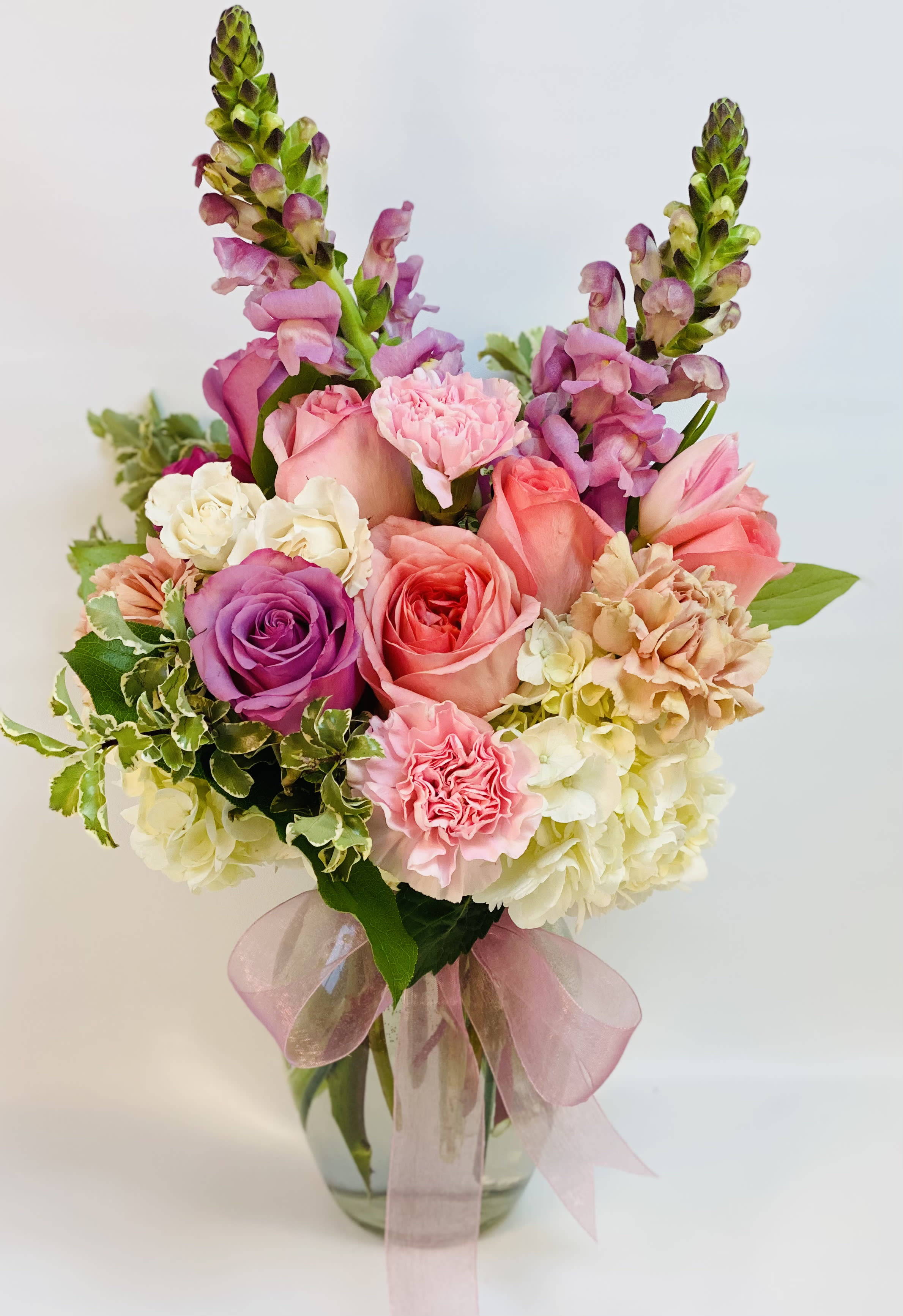Pink and purple bouquet in a glass vase with a pink ribbon