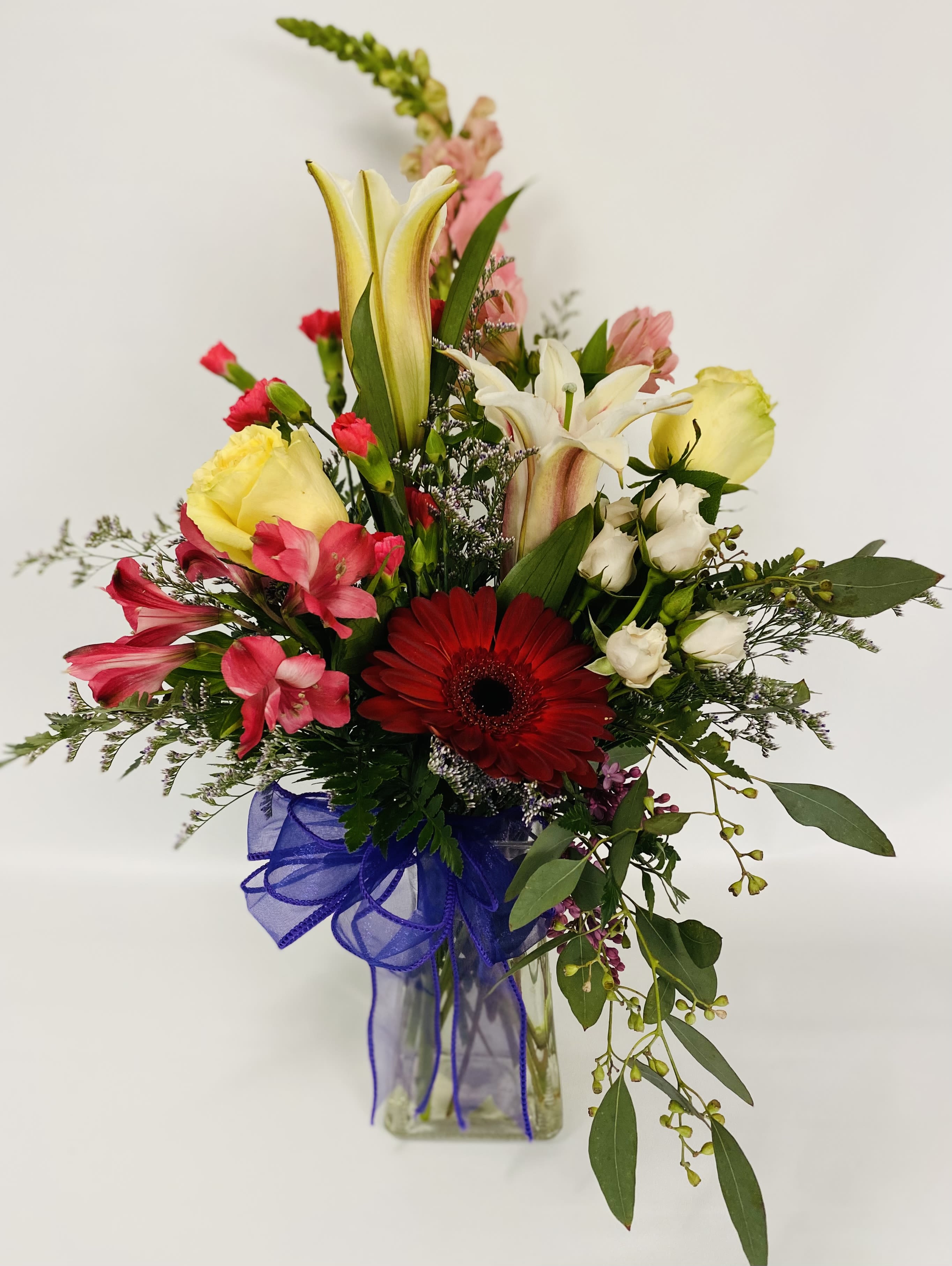 Mixed bouquet with lilies, gerbera daisy, and pink flowers in a glass vase