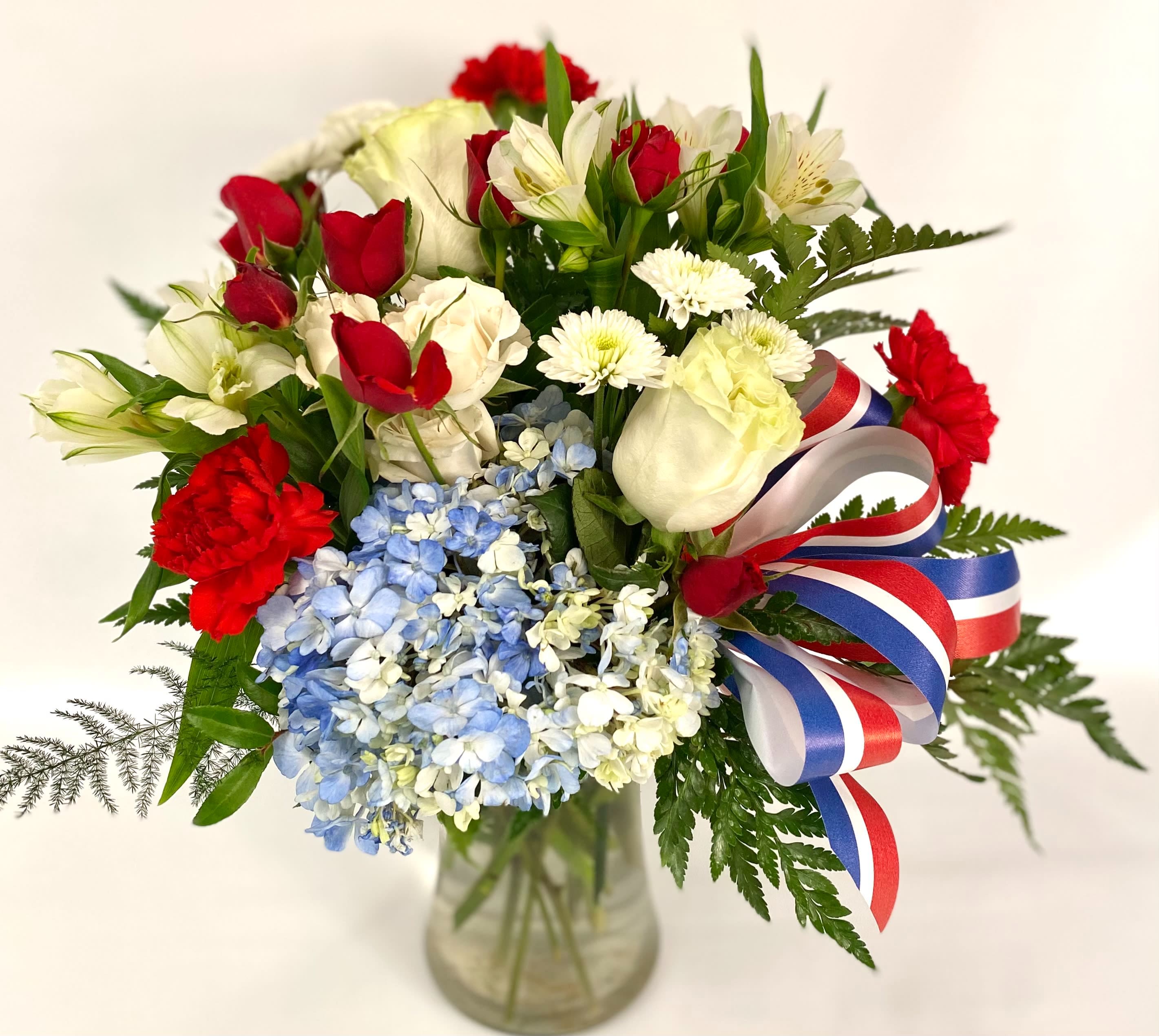 Bouquet of red and white flowers with blue hydrangeas in a glass vase