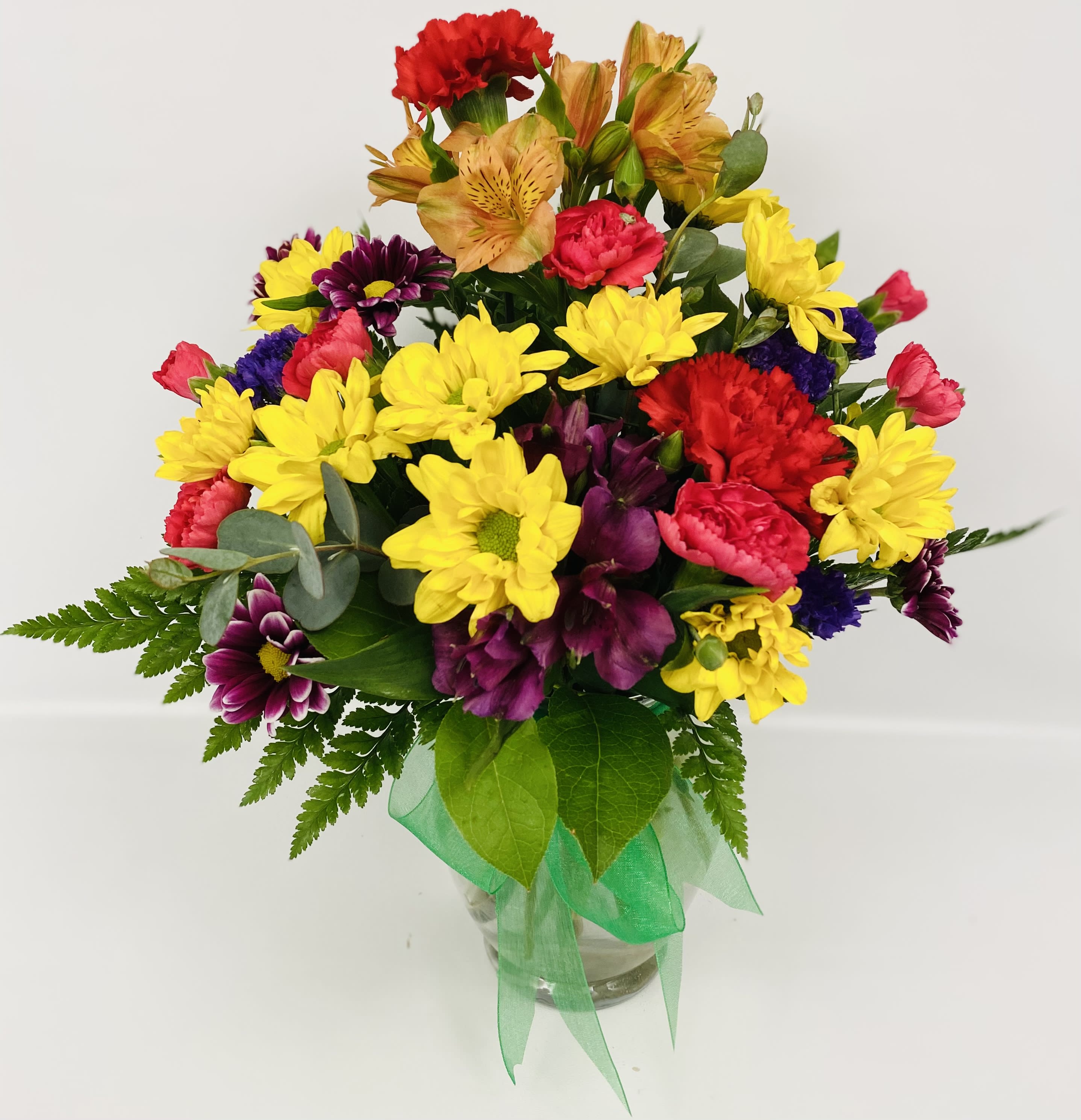 Colorful mixed bouquet in a clear glass vase with a green ribbon