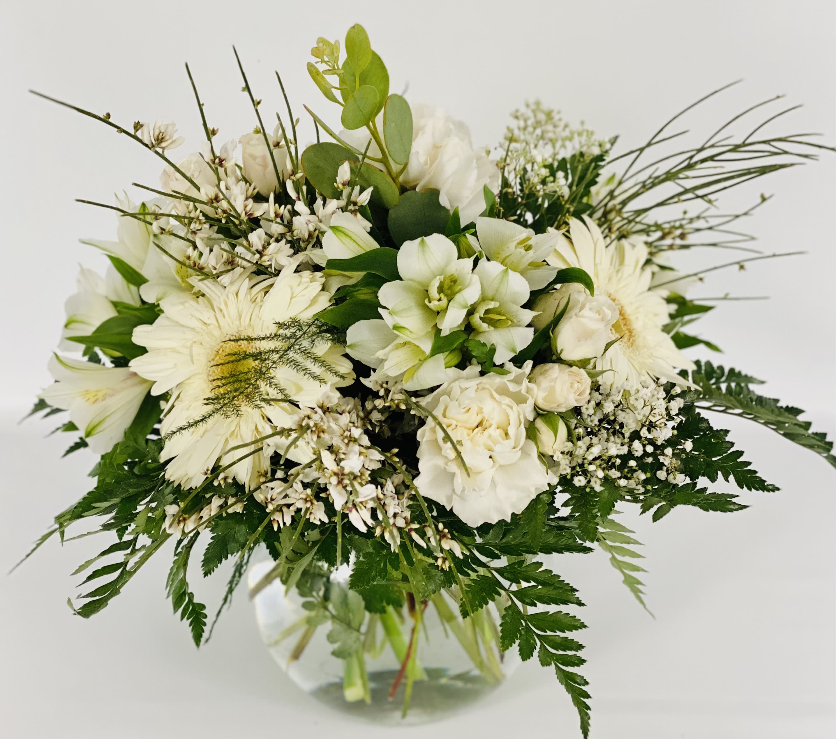 White floral bouquet in a clear glass vase with mixed greenery