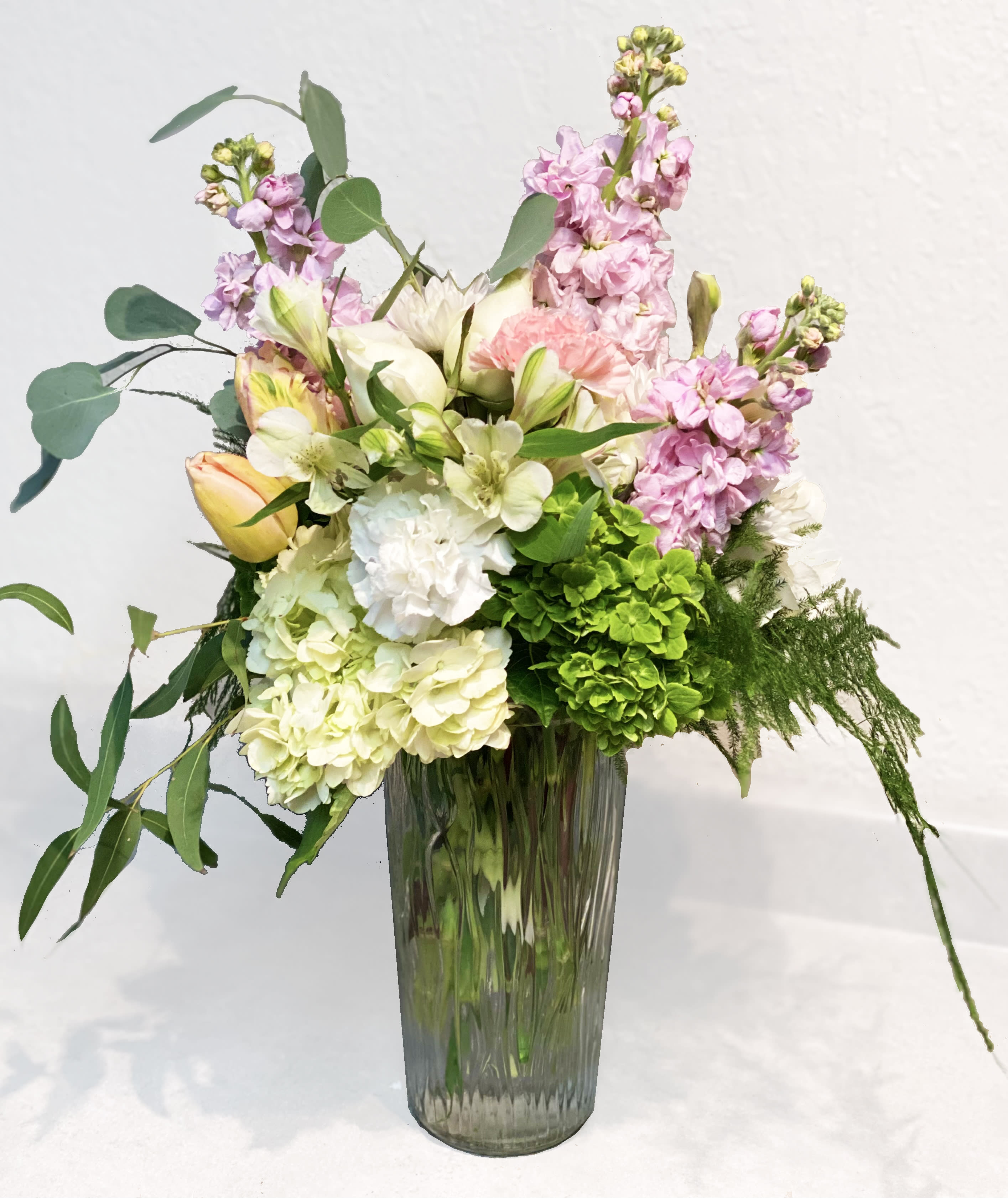 Pastel floral arrangement in a tall glass vase with pink and white blooms