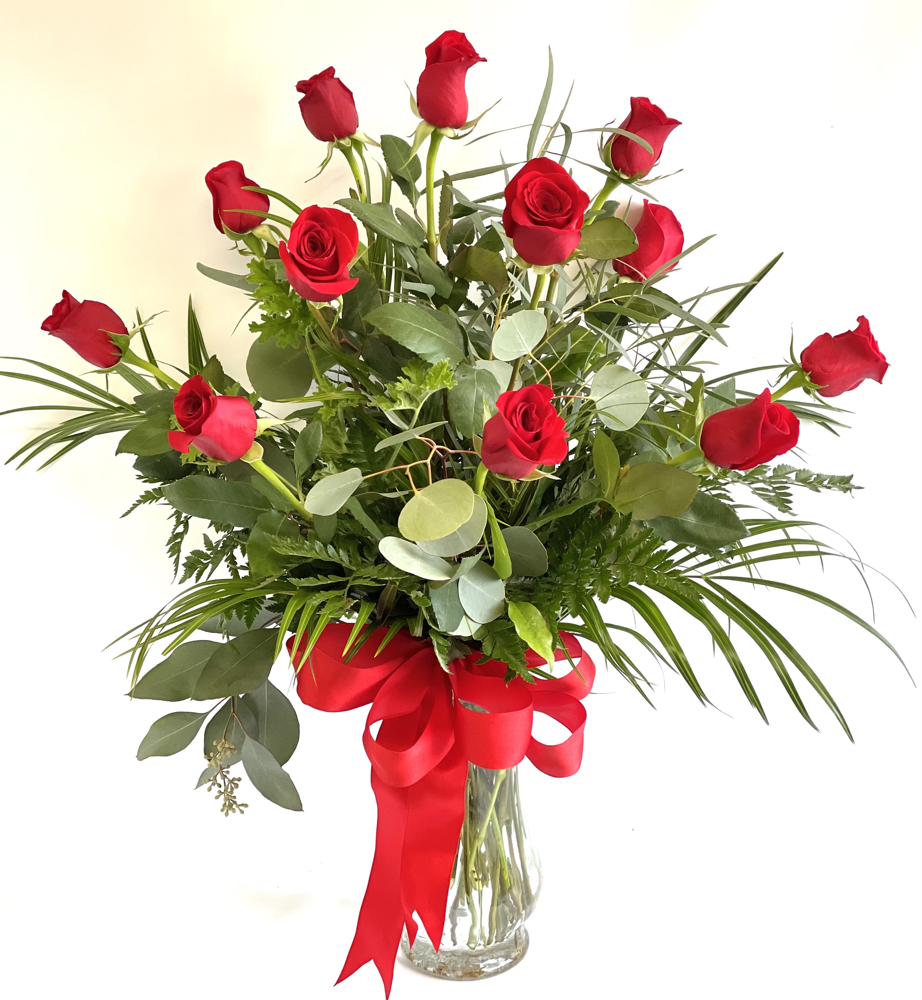Bouquet of red roses in a clear glass vase with a red ribbon