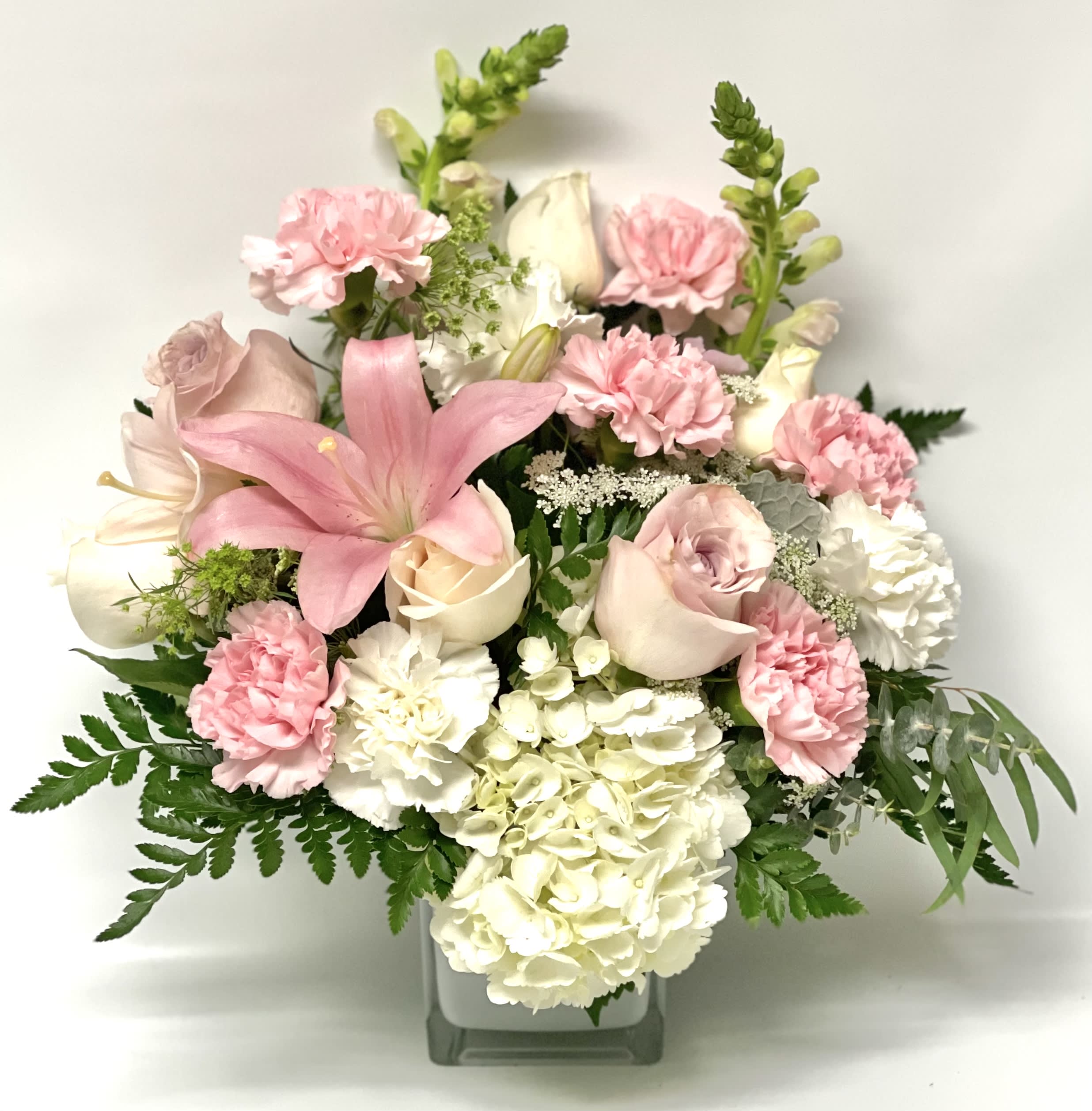 Pink and white floral arrangement in a square glass vase