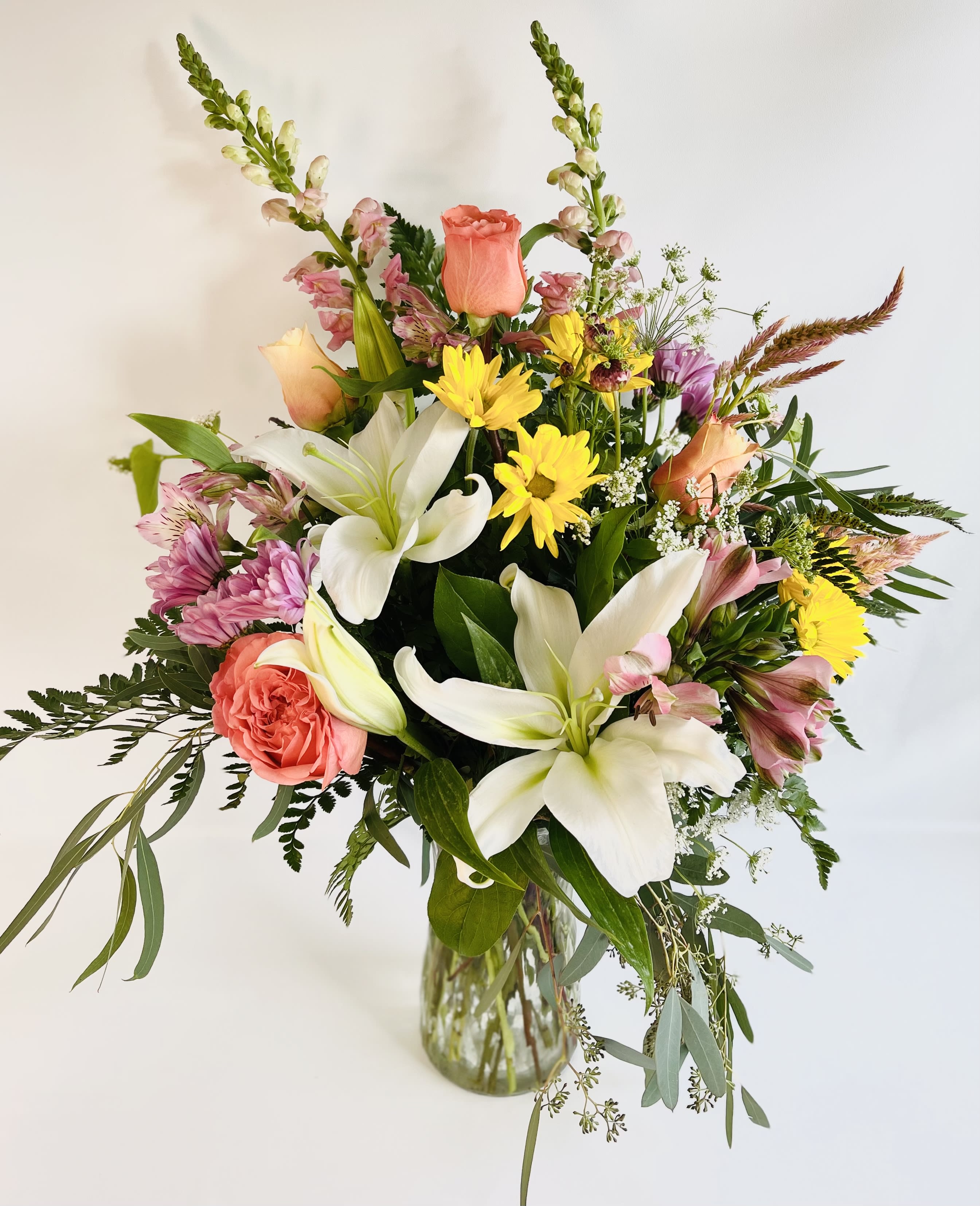 Mixed bouquet of lilies, roses, and daisies in a glass vase