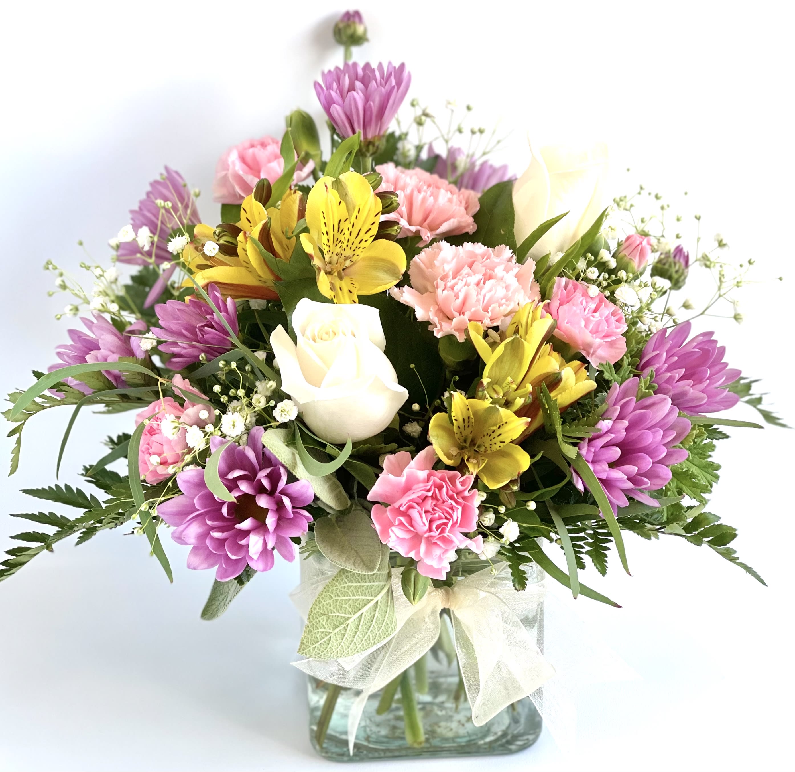 Mixed bouquet of pink, purple, yellow, and white flowers in a glass vase