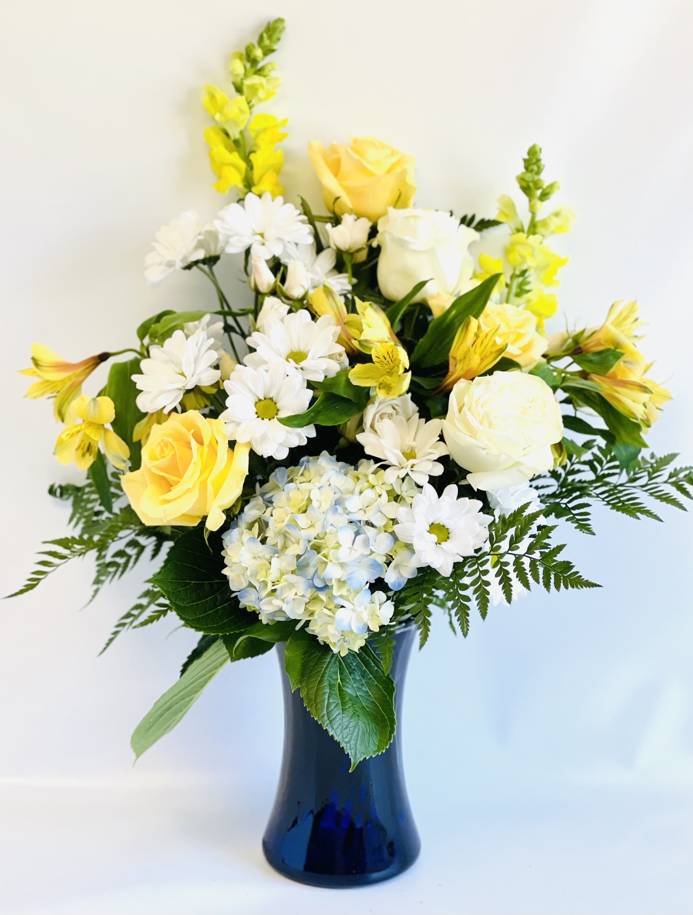 Yellow and white flowers arranged in a blue vase