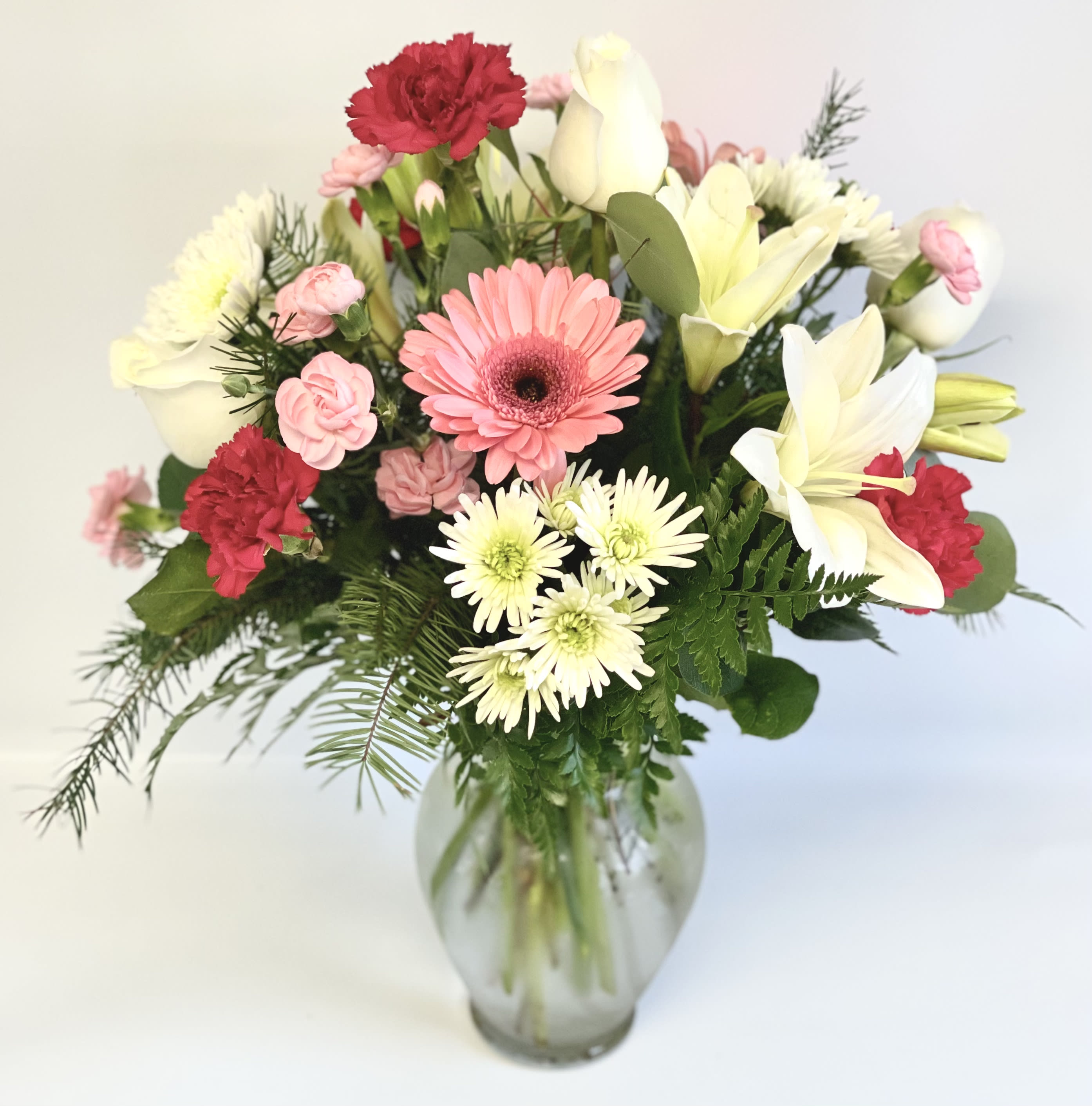 Mixed bouquet of pink, white, and red flowers in a glass vase