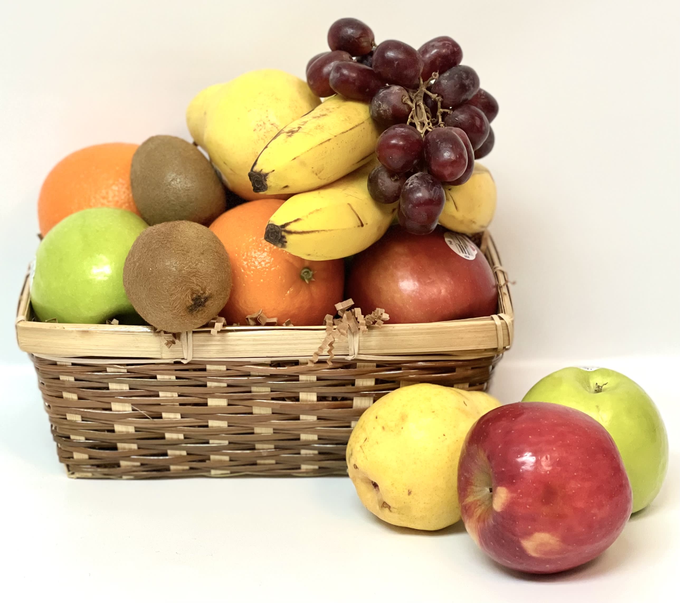 Basket of assorted fruit with grapes, bananas, apples, oranges, and kiwis