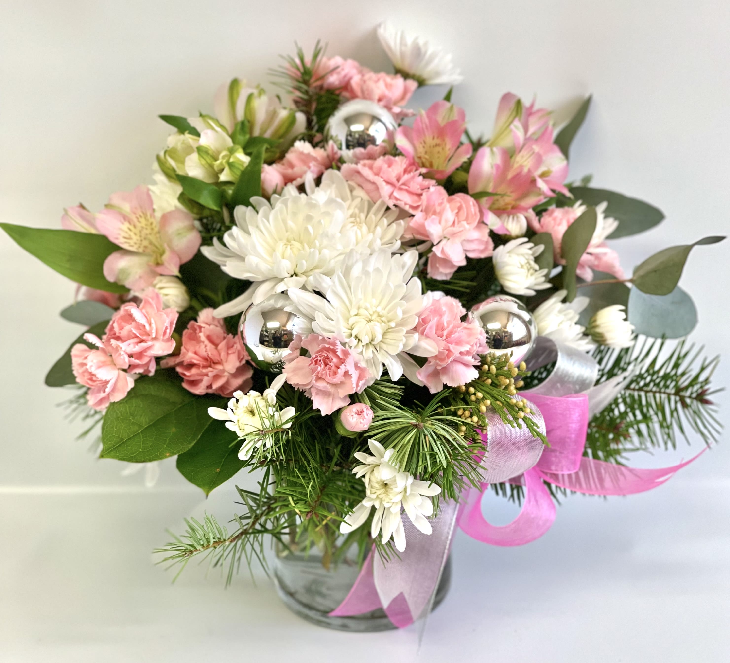 Pink and white bouquet in a glass vase with silver ornaments and ribbon