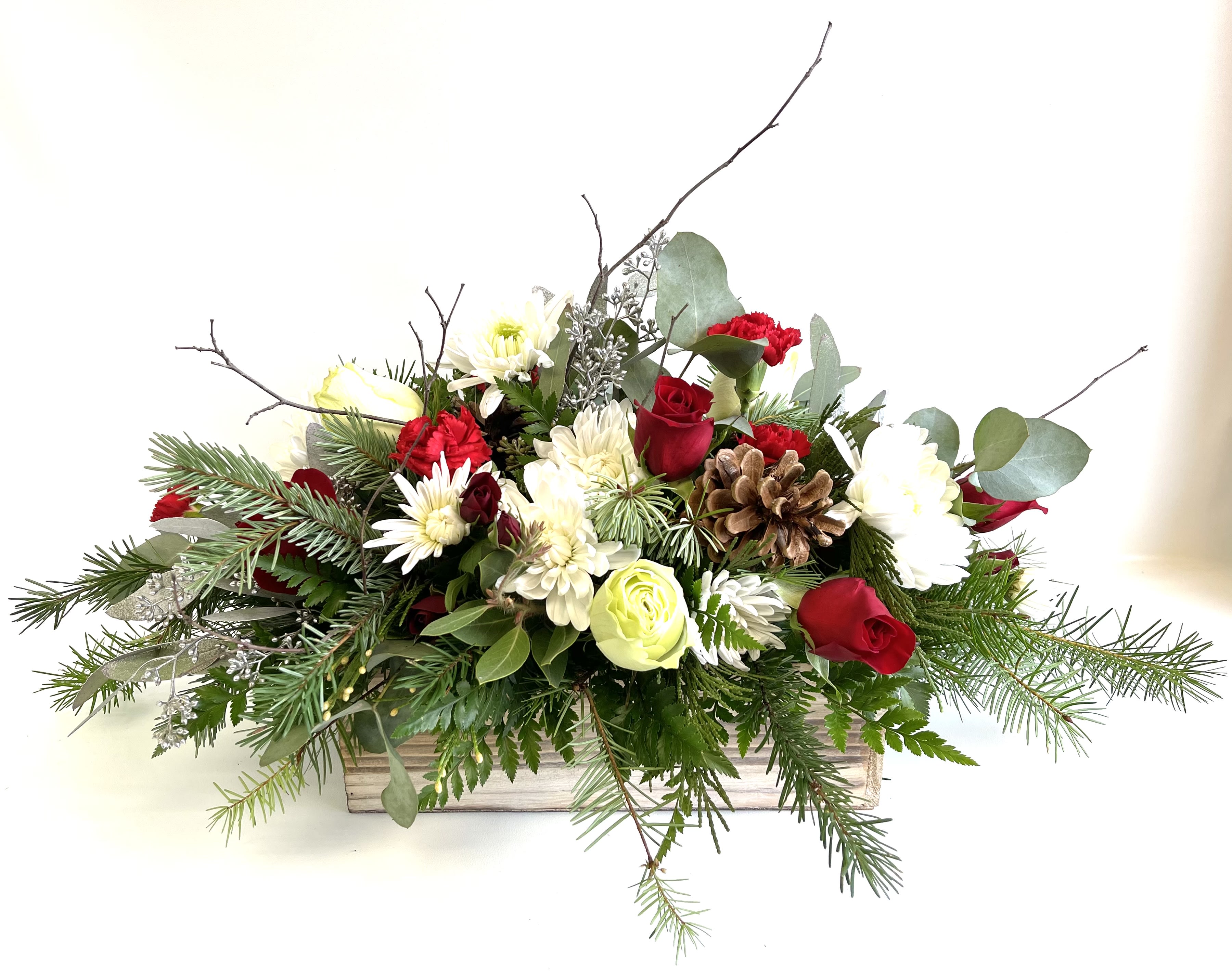 Holiday floral arrangement in a wooden box with red and white blooms