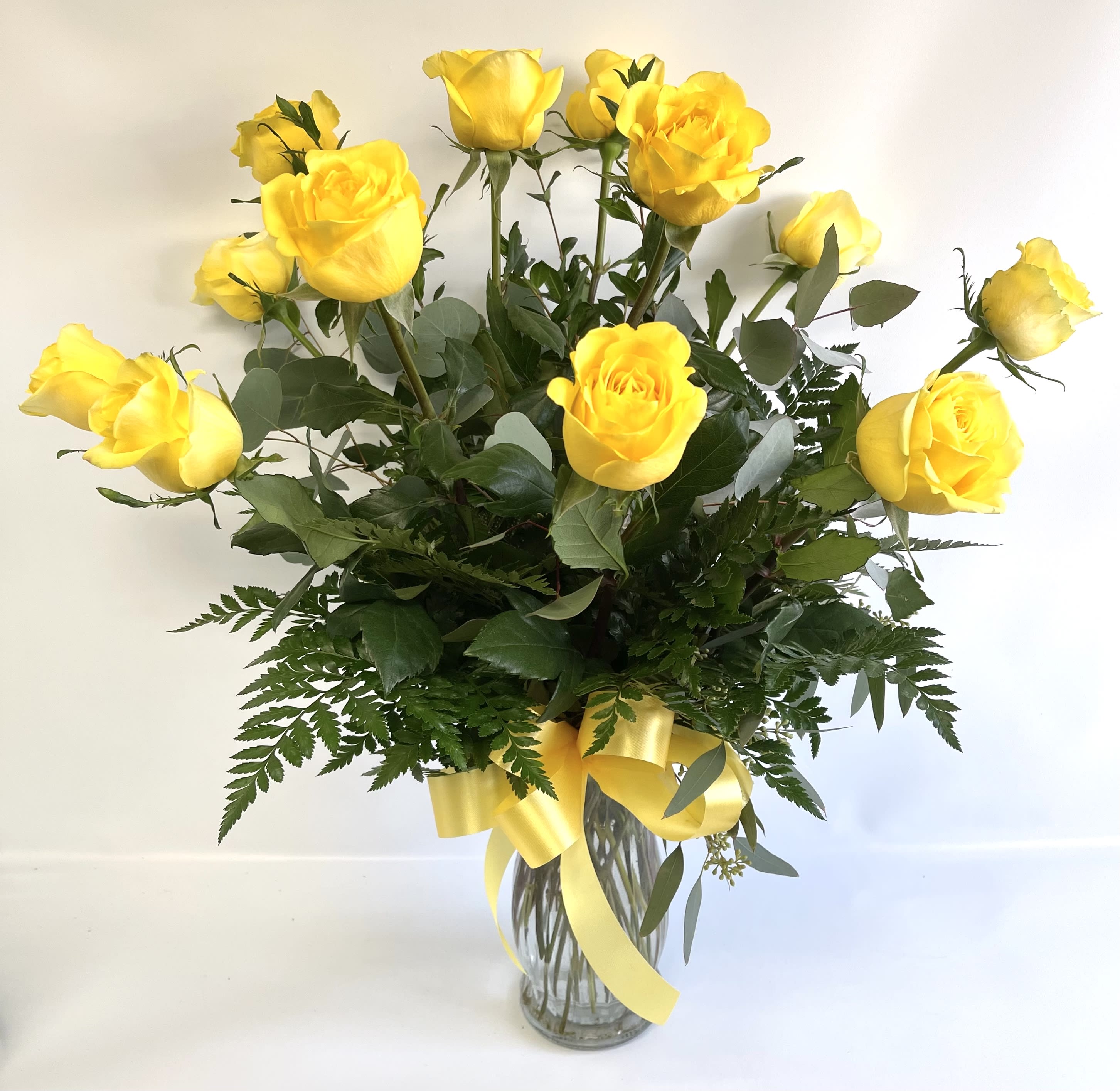 Yellow roses in a clear glass vase with a yellow ribbon