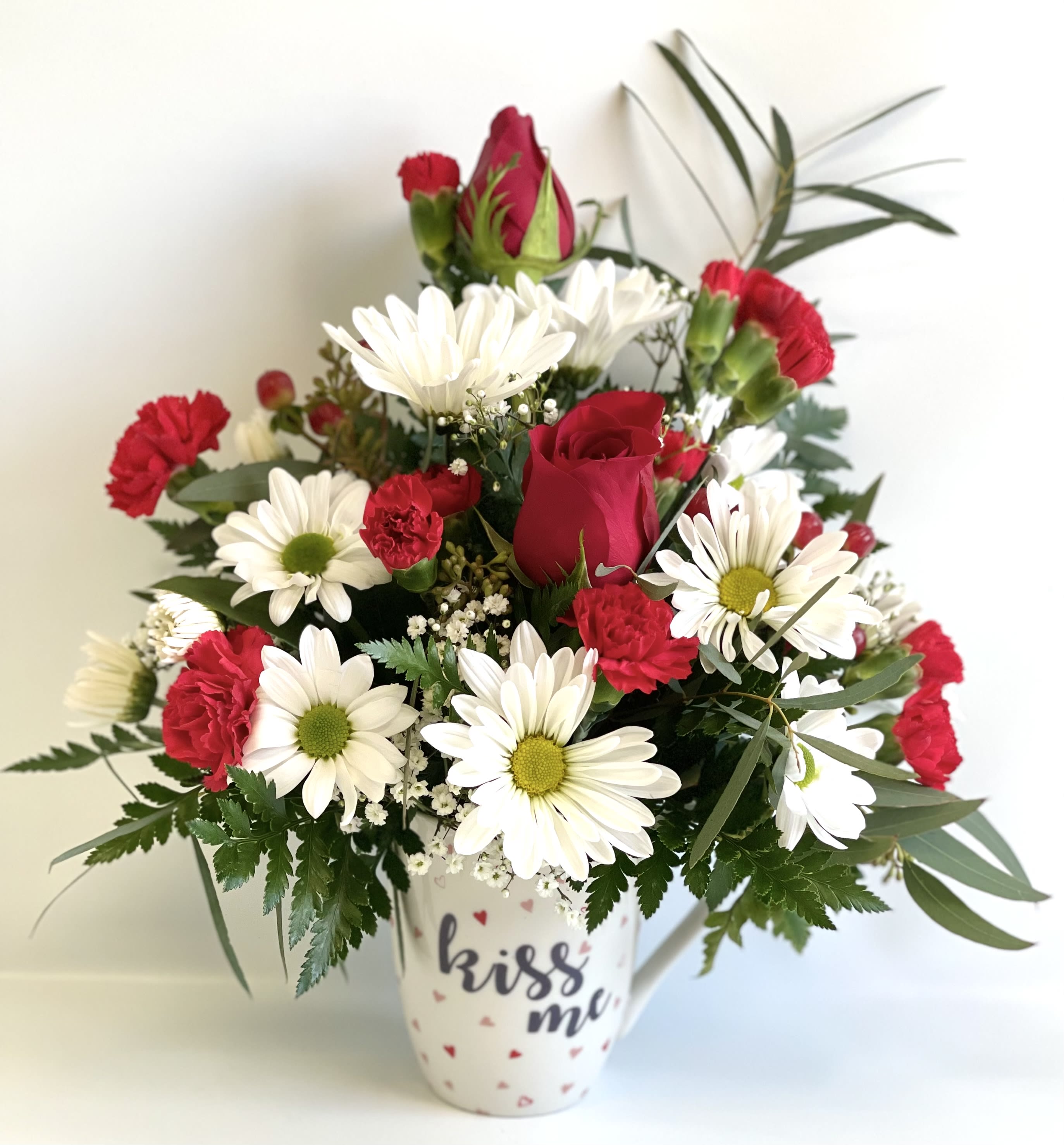 Red roses and white daisies in a white mug vase
