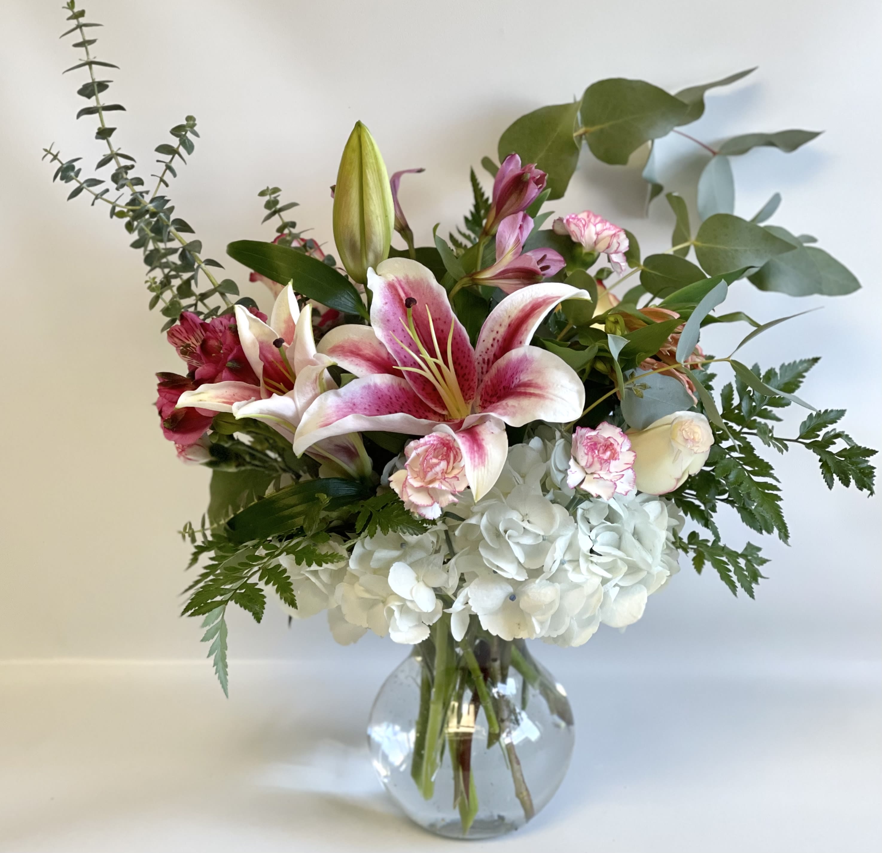 Pink lilies and white hydrangeas in a clear glass vase
