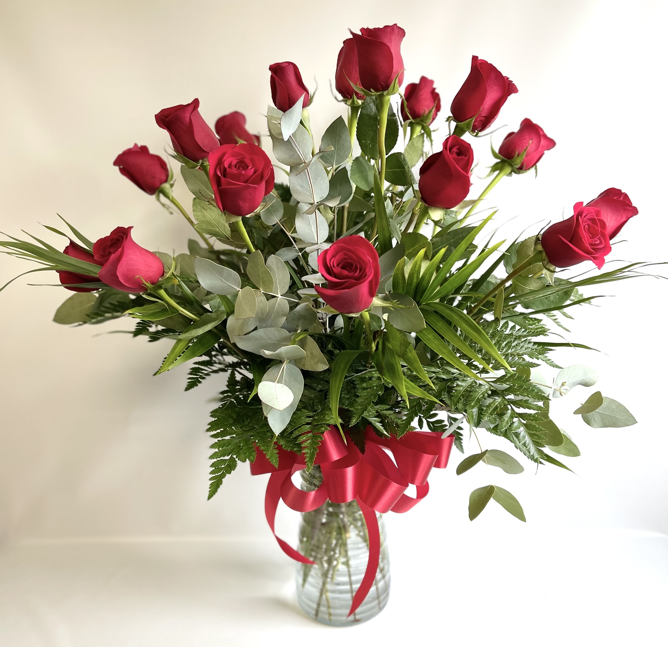 Bouquet of red roses in a glass vase with a red ribbon
