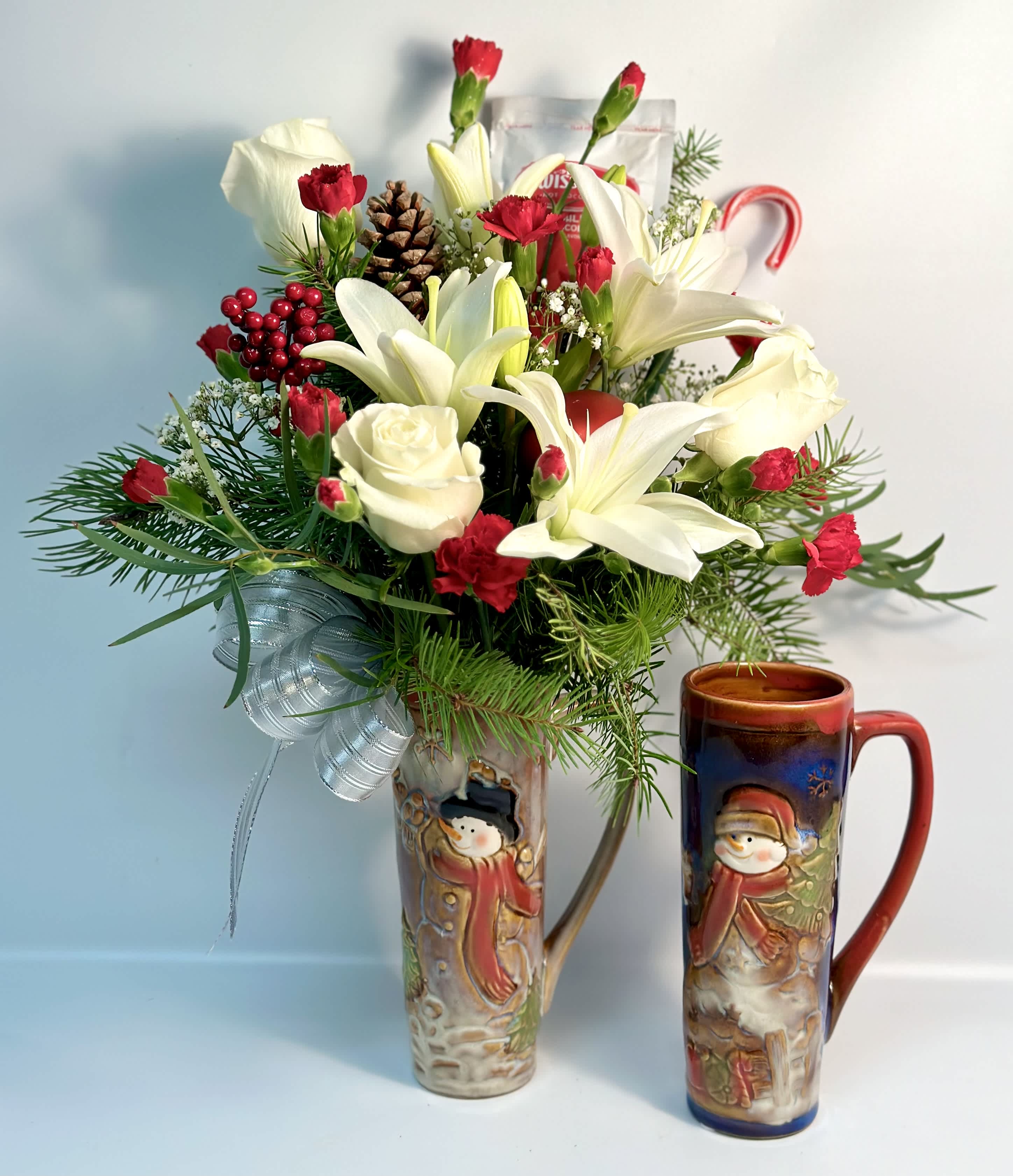 Holiday bouquet with white lilies, red carnations, and a pinecone in a decorative vase