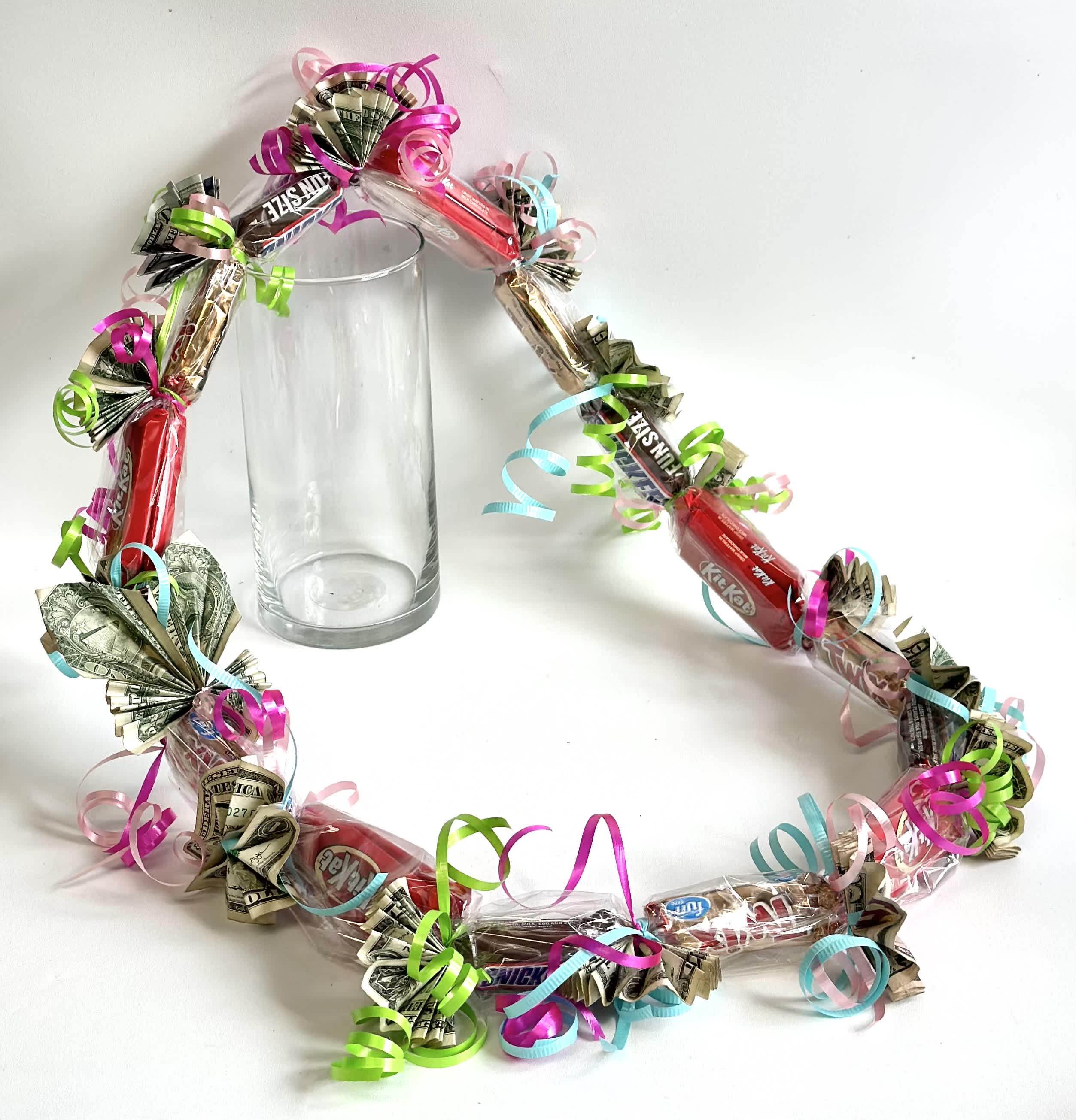 Candy and cash garland wrapped around a clear glass vase