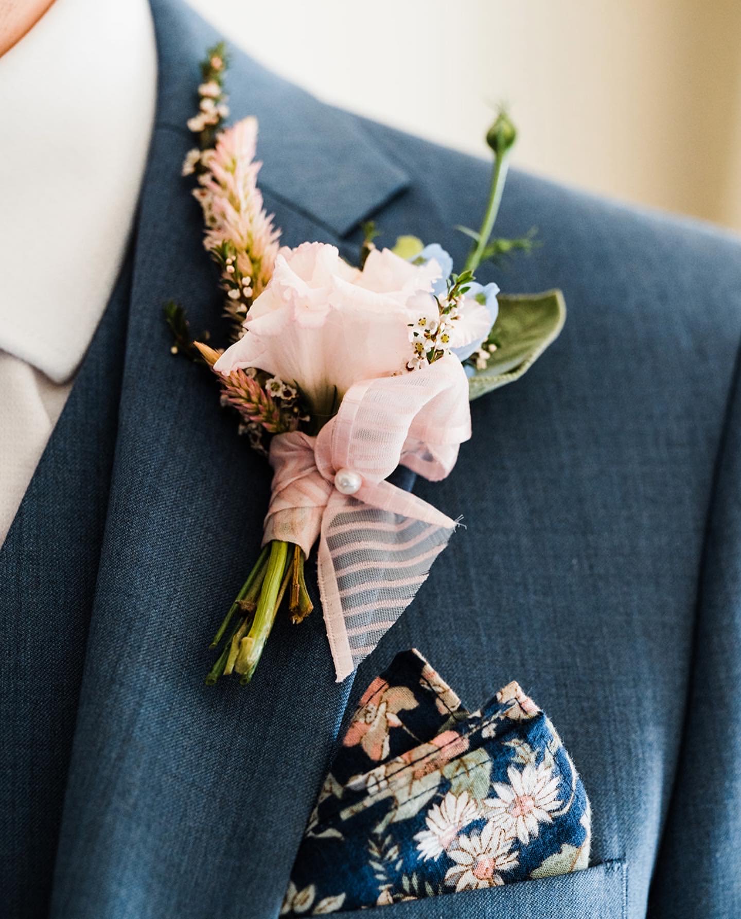 Pink boutonniere pinned to a blue suit jacket