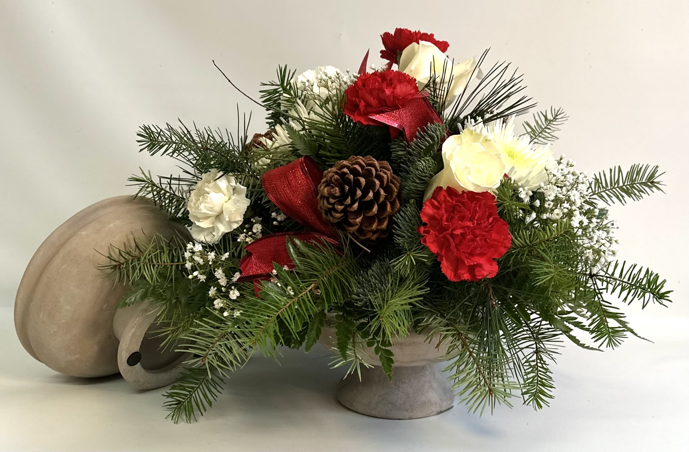 Holiday floral arrangement with red and white carnations in a stone vase