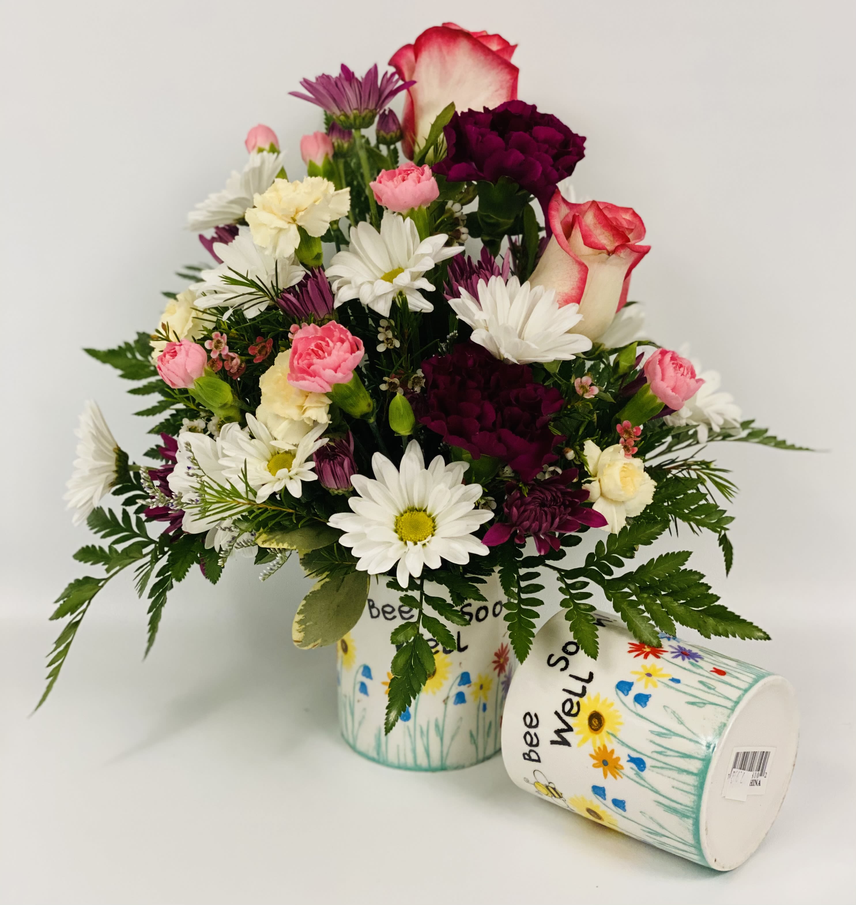 Mixed bouquet of daisies, carnations, and roses in a decorated container