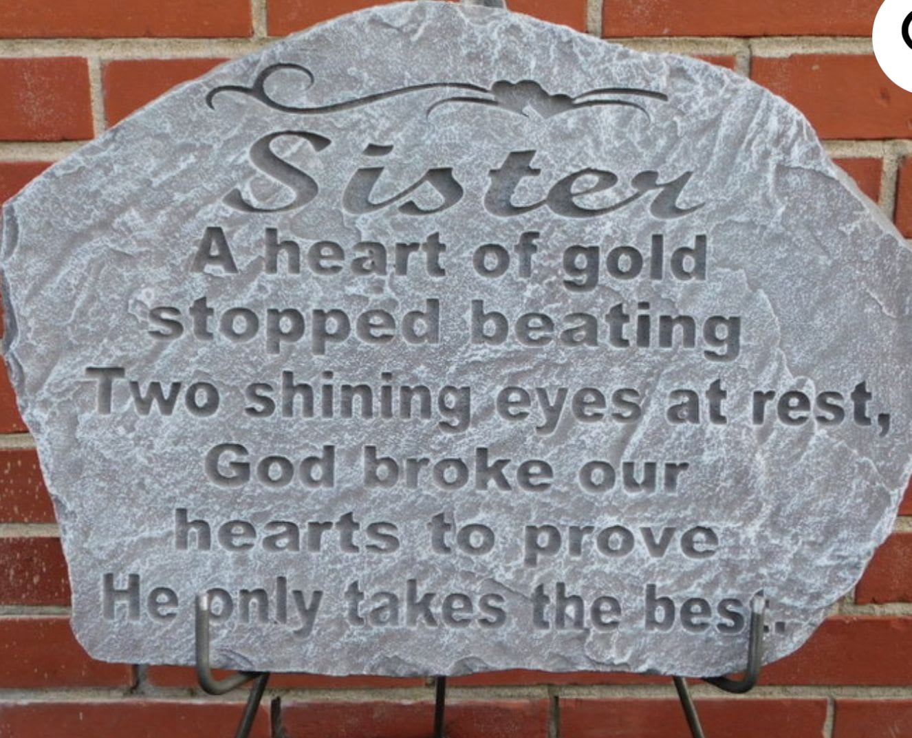 Gray memorial plaque with engraved tribute text against a brick wall