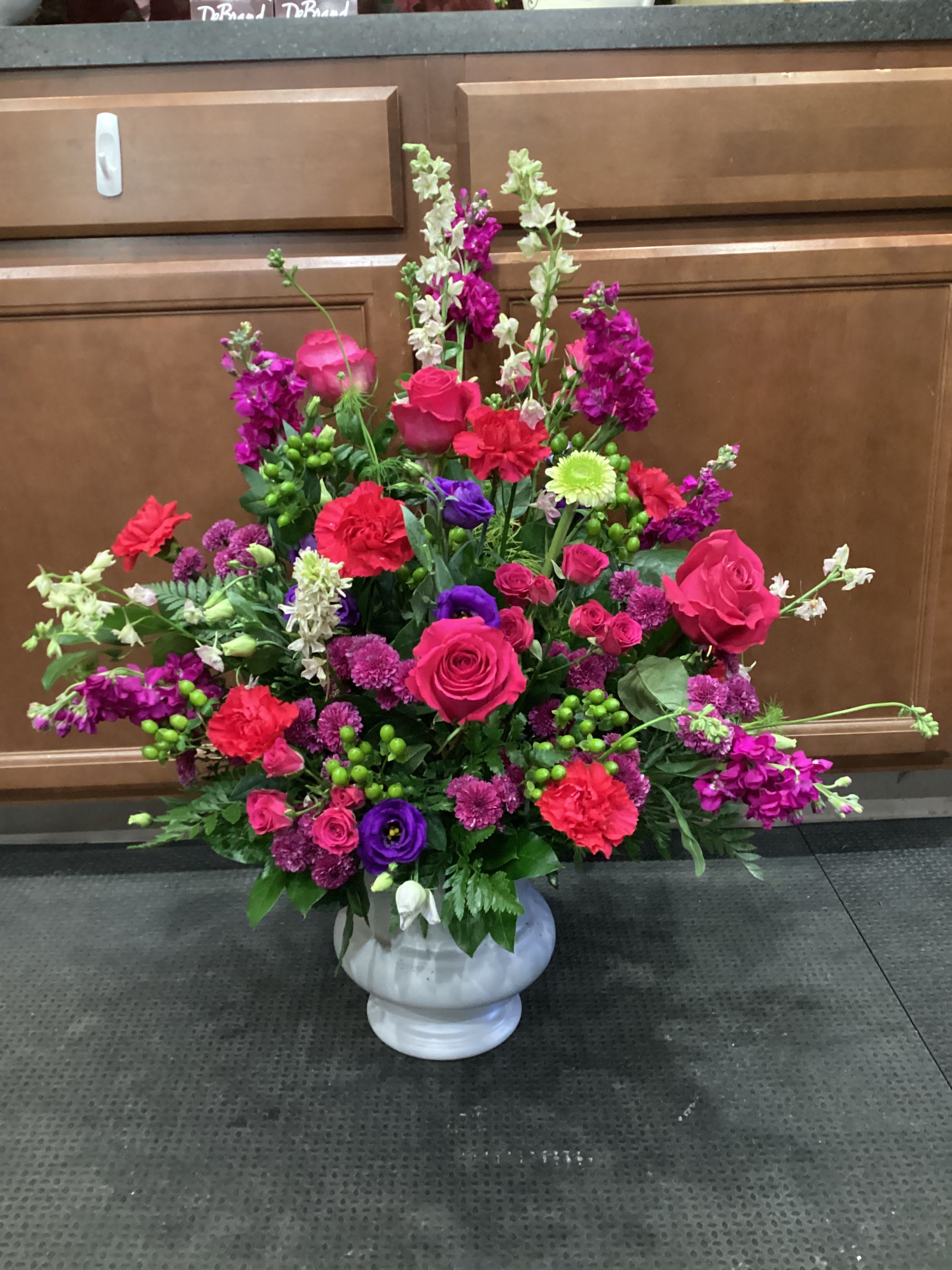 Large mixed floral arrangement in a white urn vase
