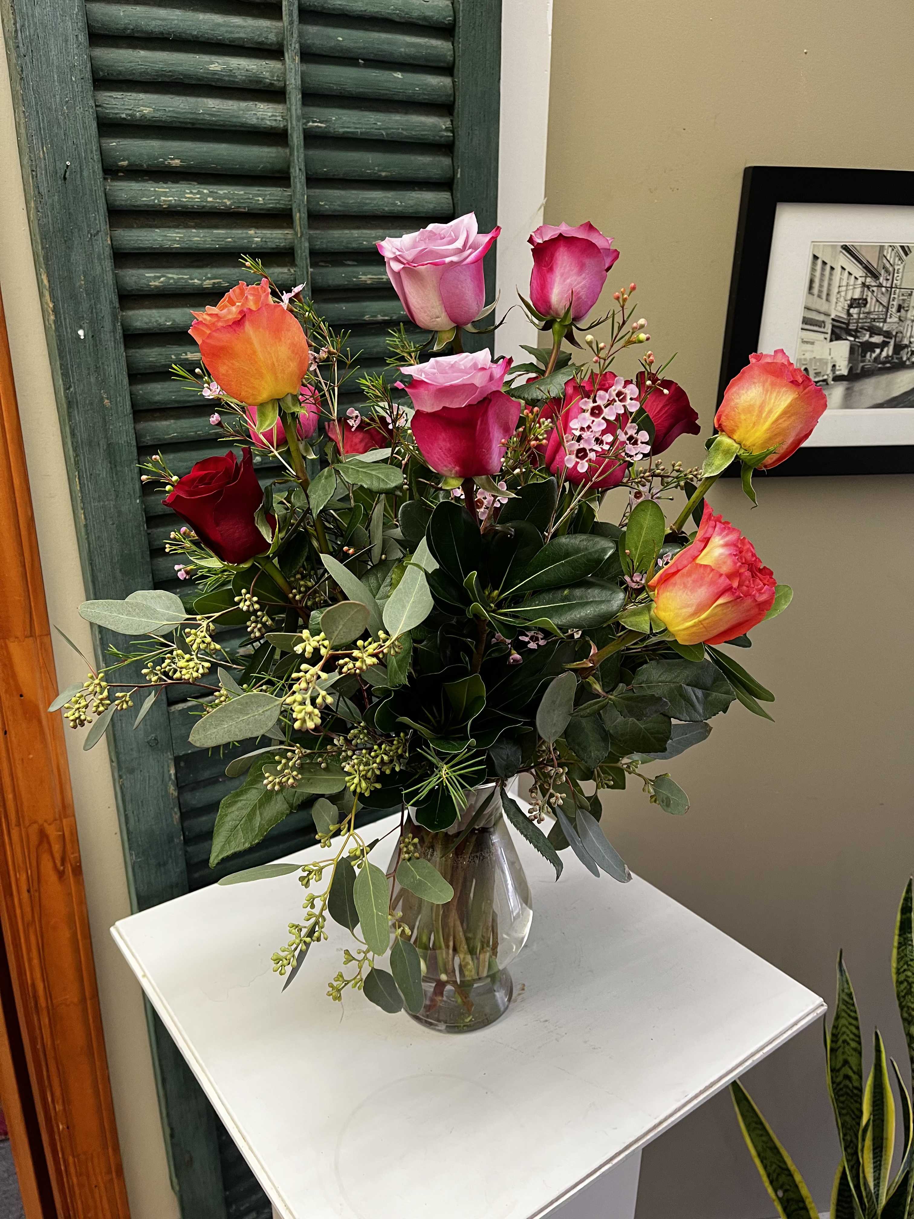 Mixed roses in a clear glass vase with greenery