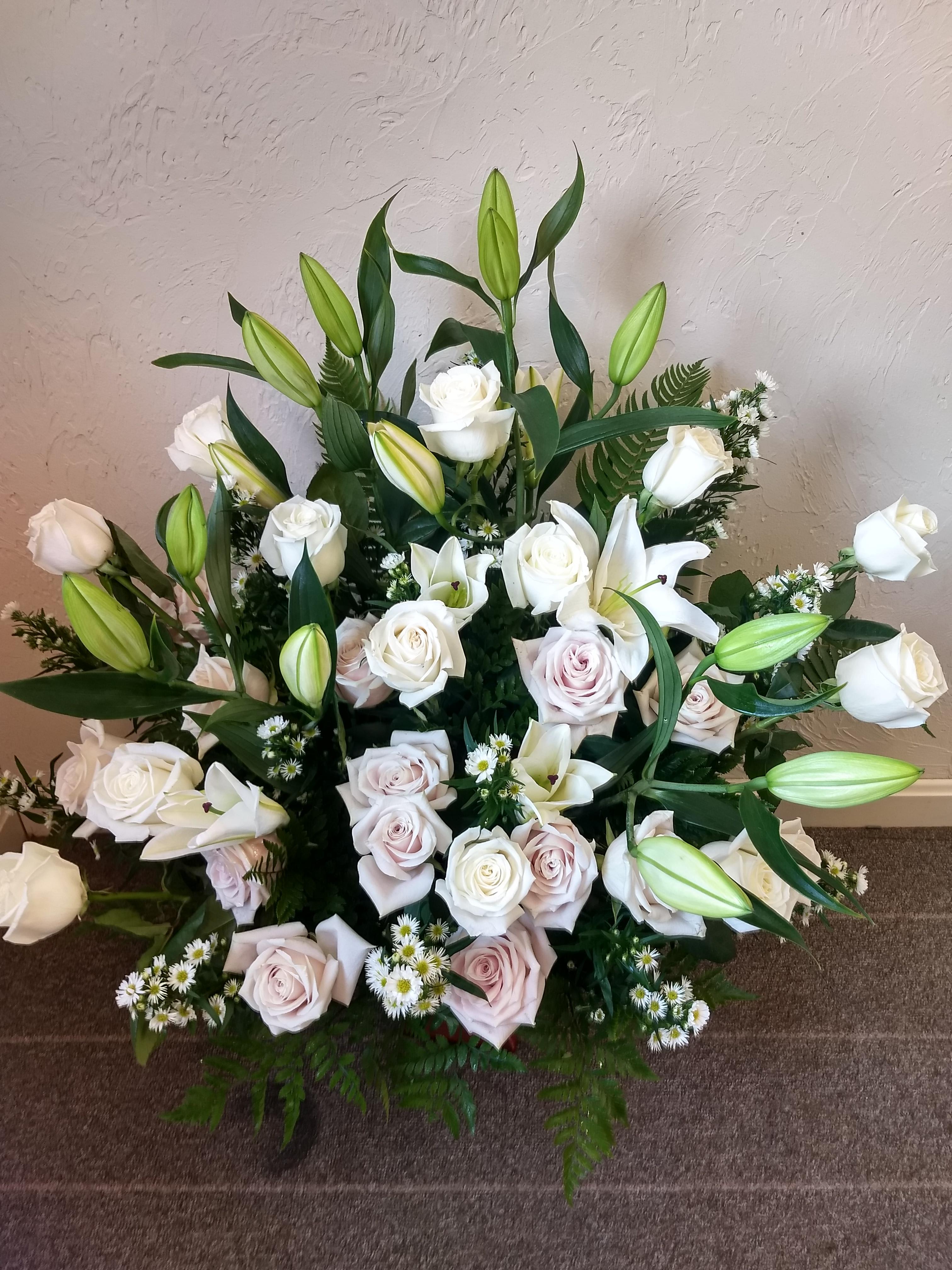 White roses and lilies arranged with greenery in a low bouquet