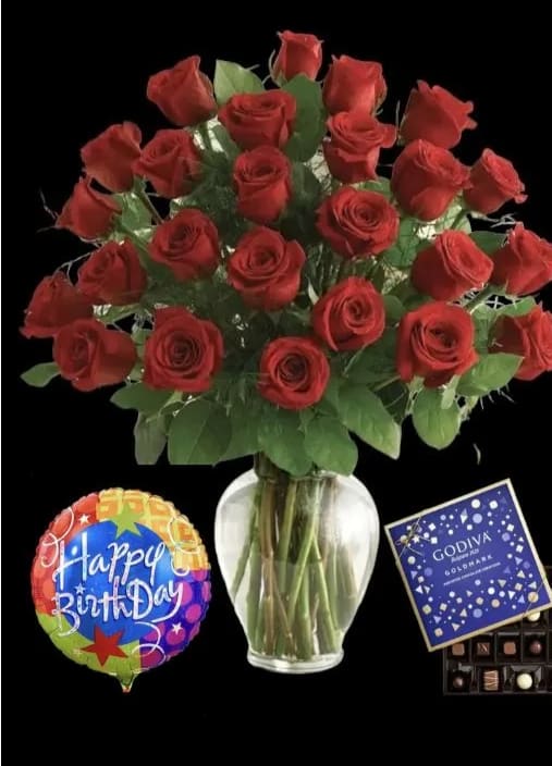 Red roses in a glass vase with a birthday balloon and chocolate box
